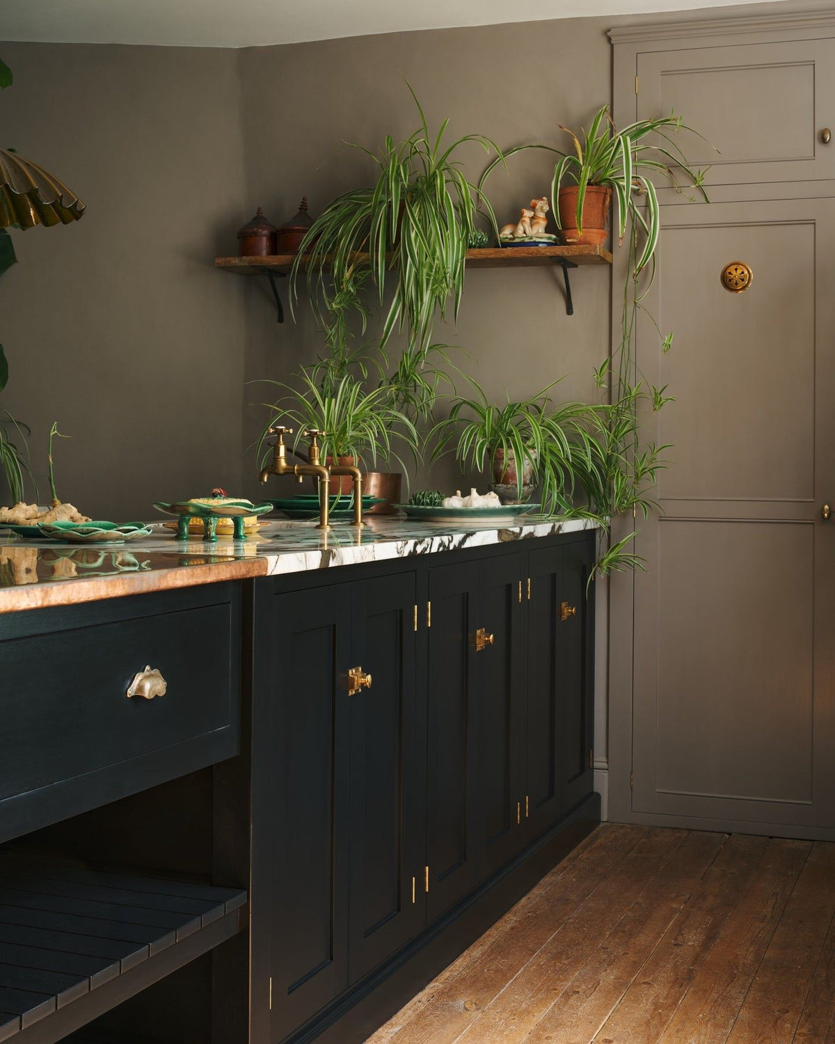 An oblique view of black painted kitchen cupboard doors with classic-style square cupboard catches in a warm burnished brass finish. TEST