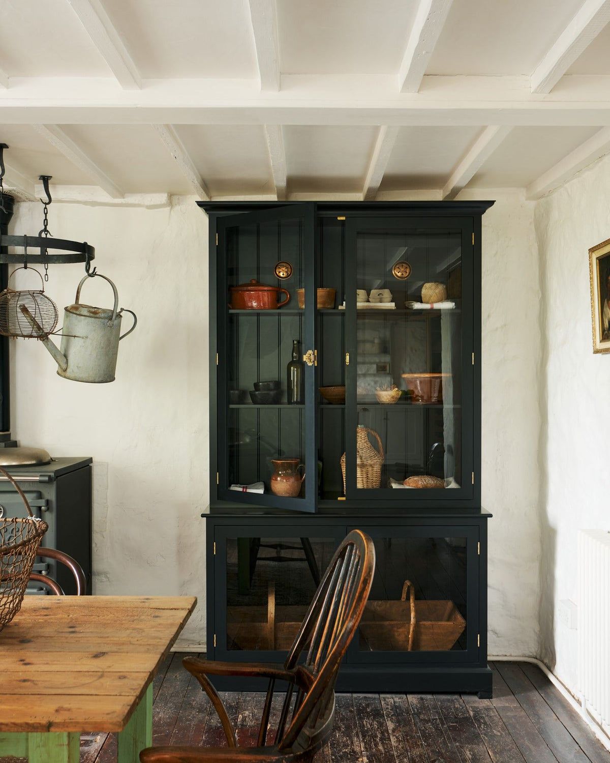 A tall museum-style black painted display cabinet with glazed doors and a pair of Victorian-inspired circular brass ventilation grilles with traditional decorative cutouts fitted to a tongue and groove-style back panel. TEST
