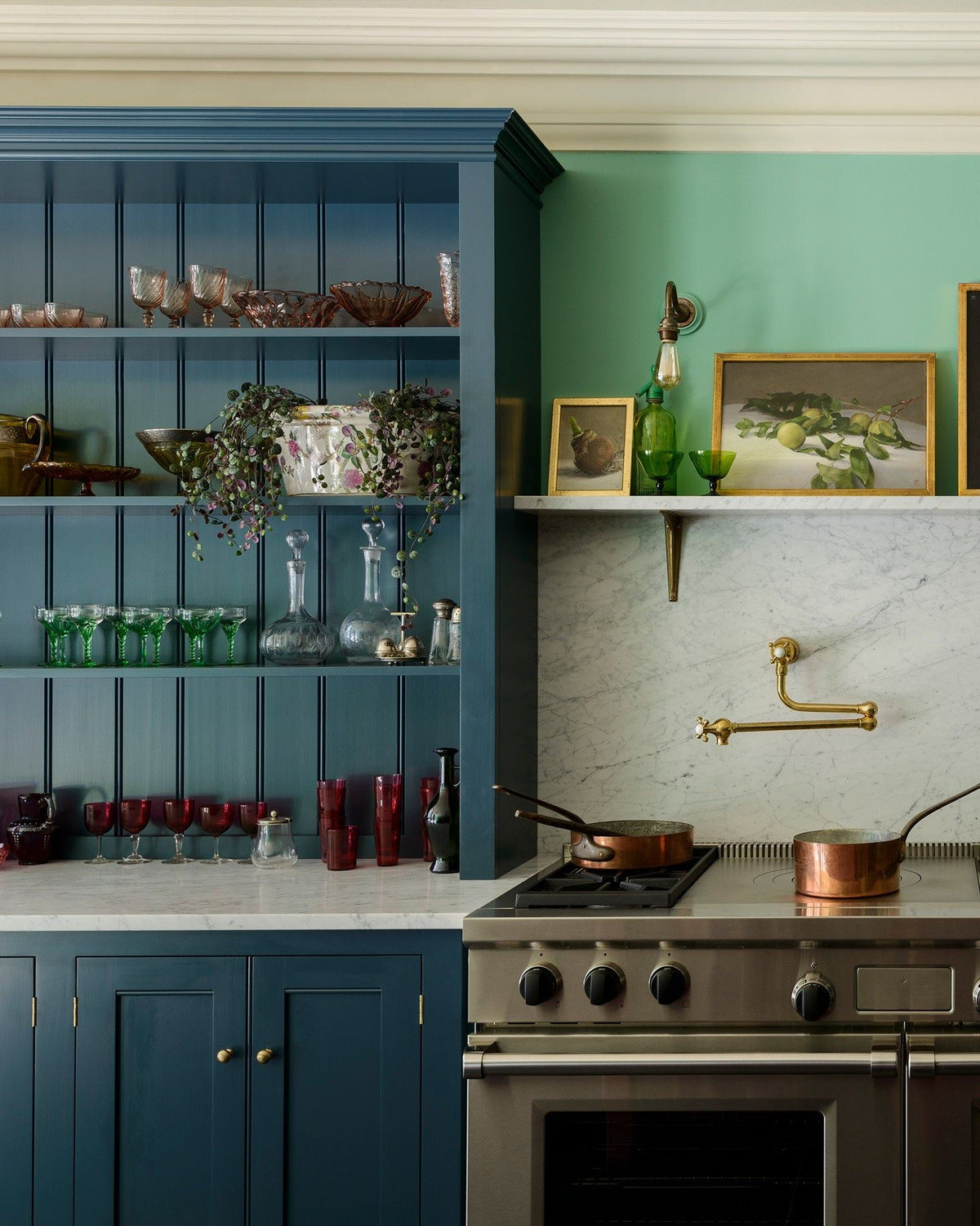 A straight-on view of Georgian-style kitchen cupboards with an open countertop stacked full of green and red coloured glasses. TEST