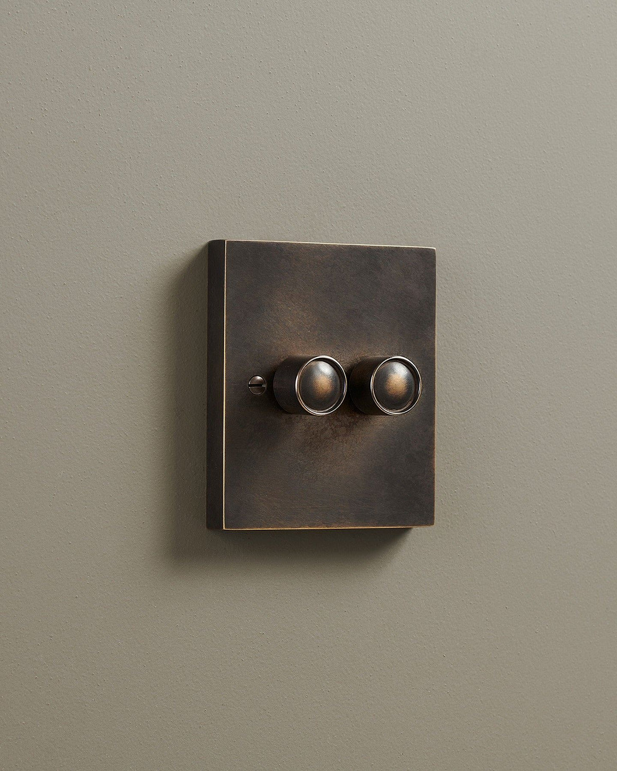 An oblique view of a 2 gang box dimmer switch in a dark oxidised brass finish. TEST