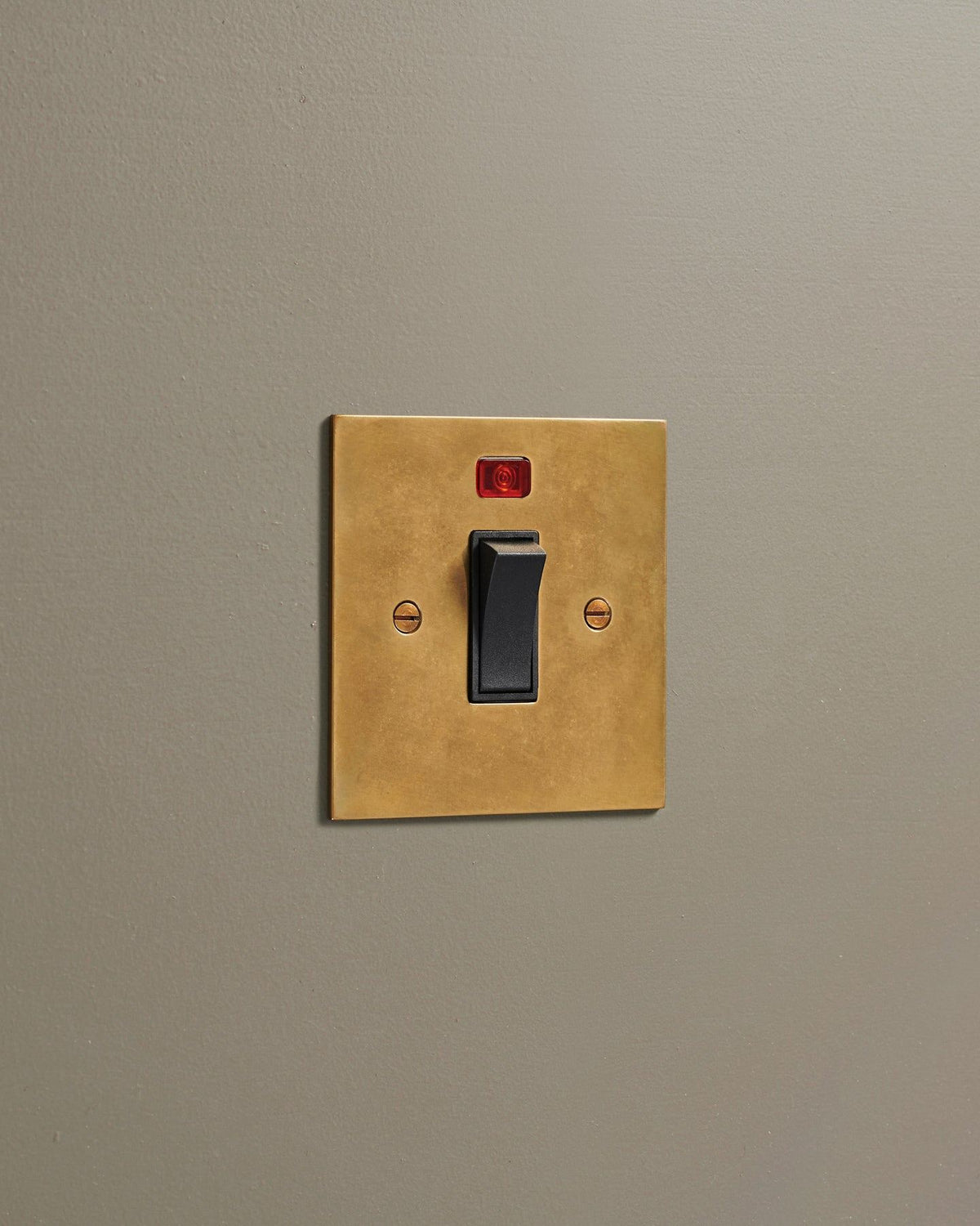 An oblique view of a classic 32 amp cooker switch in a warm burnished brass finish. TEST