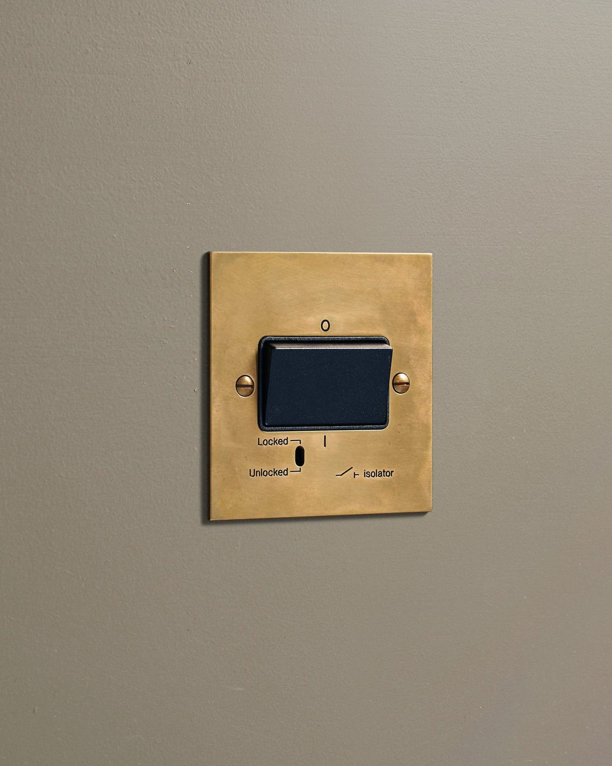 An oblique view of a classic extractor fan isolator switch in a warm burnished brass finish. TEST