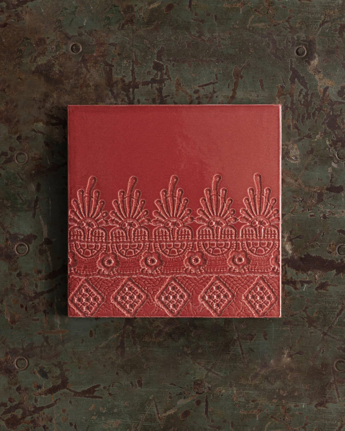 Red embossed book on a textured green surface. | Flanders Square TEST