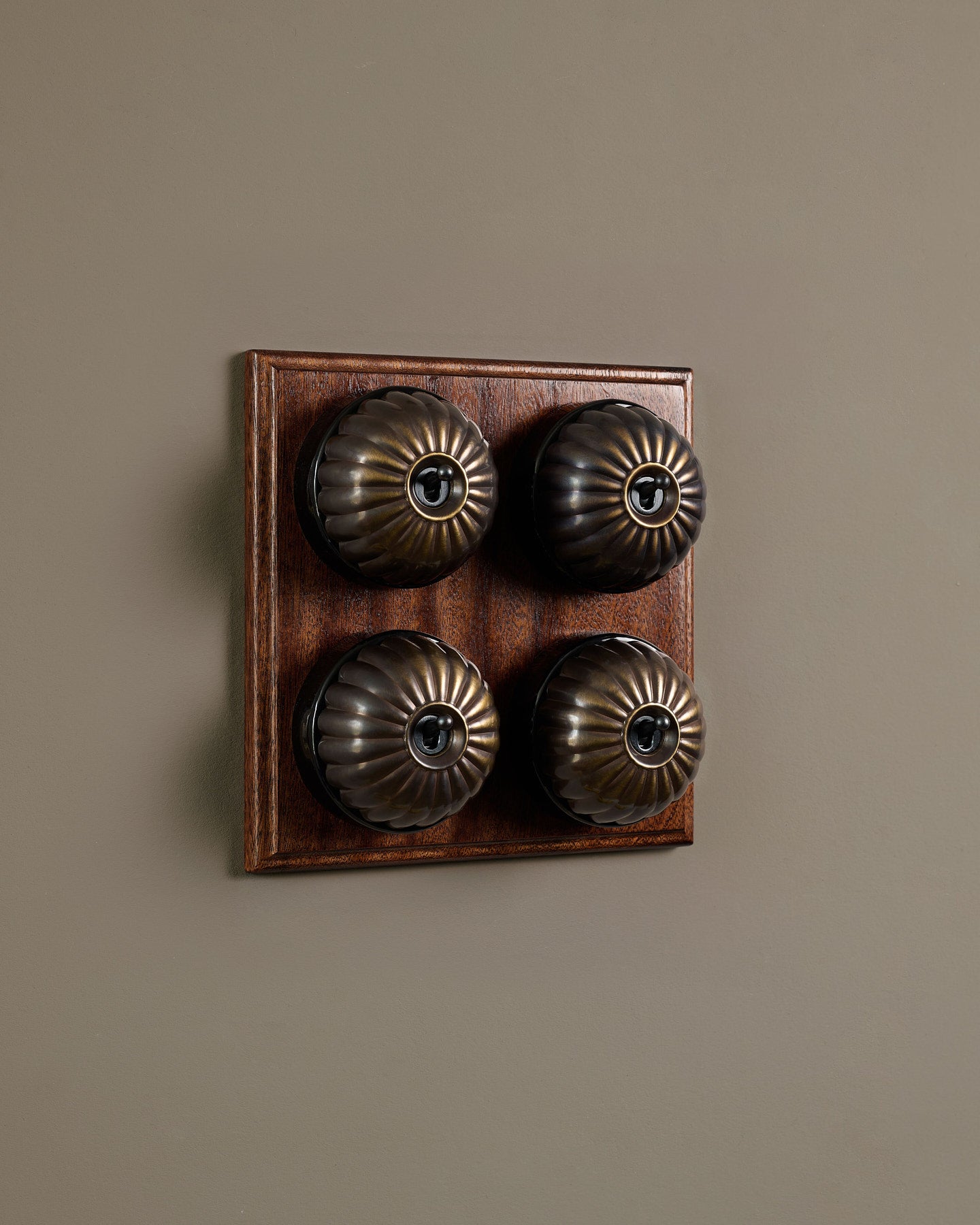 The Jelly Toggle Switch (4 Gang Bank & Mahogany Finish Pattress) - Oxidised Brass with Black Base.