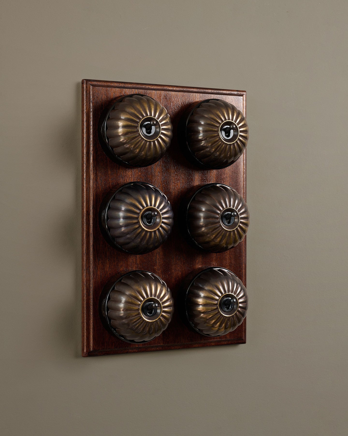 The Jelly Toggle Switch (6 Gang & Mahogany Finish Pattress) - Oxidised Brass with Black Base.