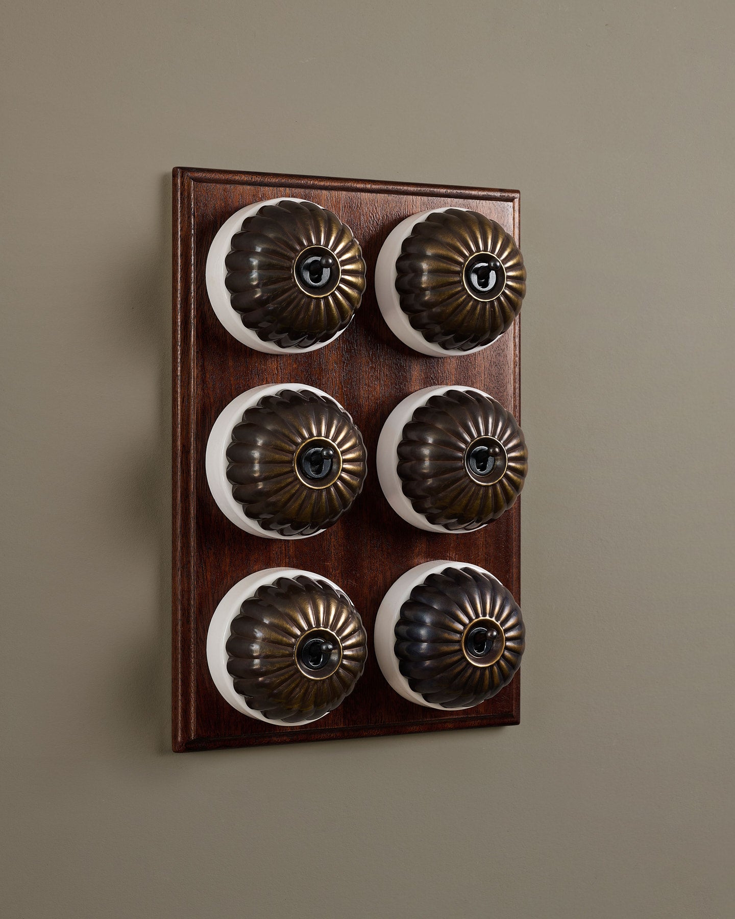 The Jelly Toggle Switch (6 Gang & Mahogany Finish Pattress) - Oxidised Brass with White Base.