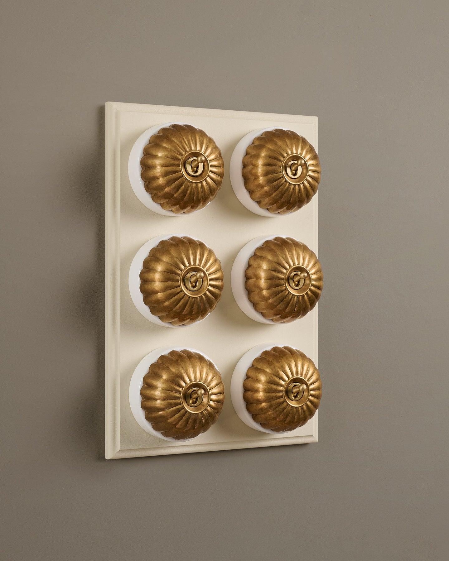 The Jelly Toggle Switch (6 Gang & Primed Maple Pattress) - Aged Brass with White Base.