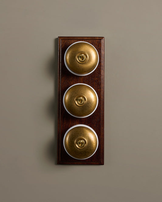 The Dolly Toggle Switch (3 Gang & Mahogany Finish Pattress) - Aged Brass with White Base.