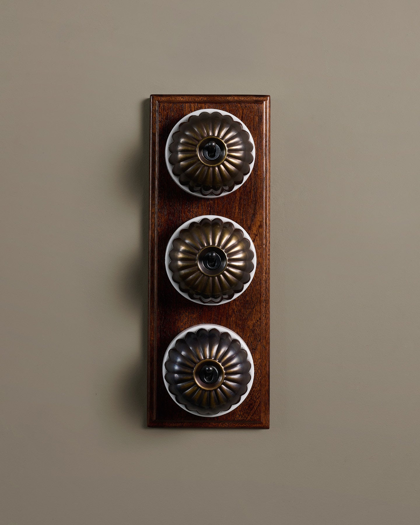 The Jelly Toggle Switch (3 Gang & Mahogany Finish Pattress) - Oxidised Brass with White Base.