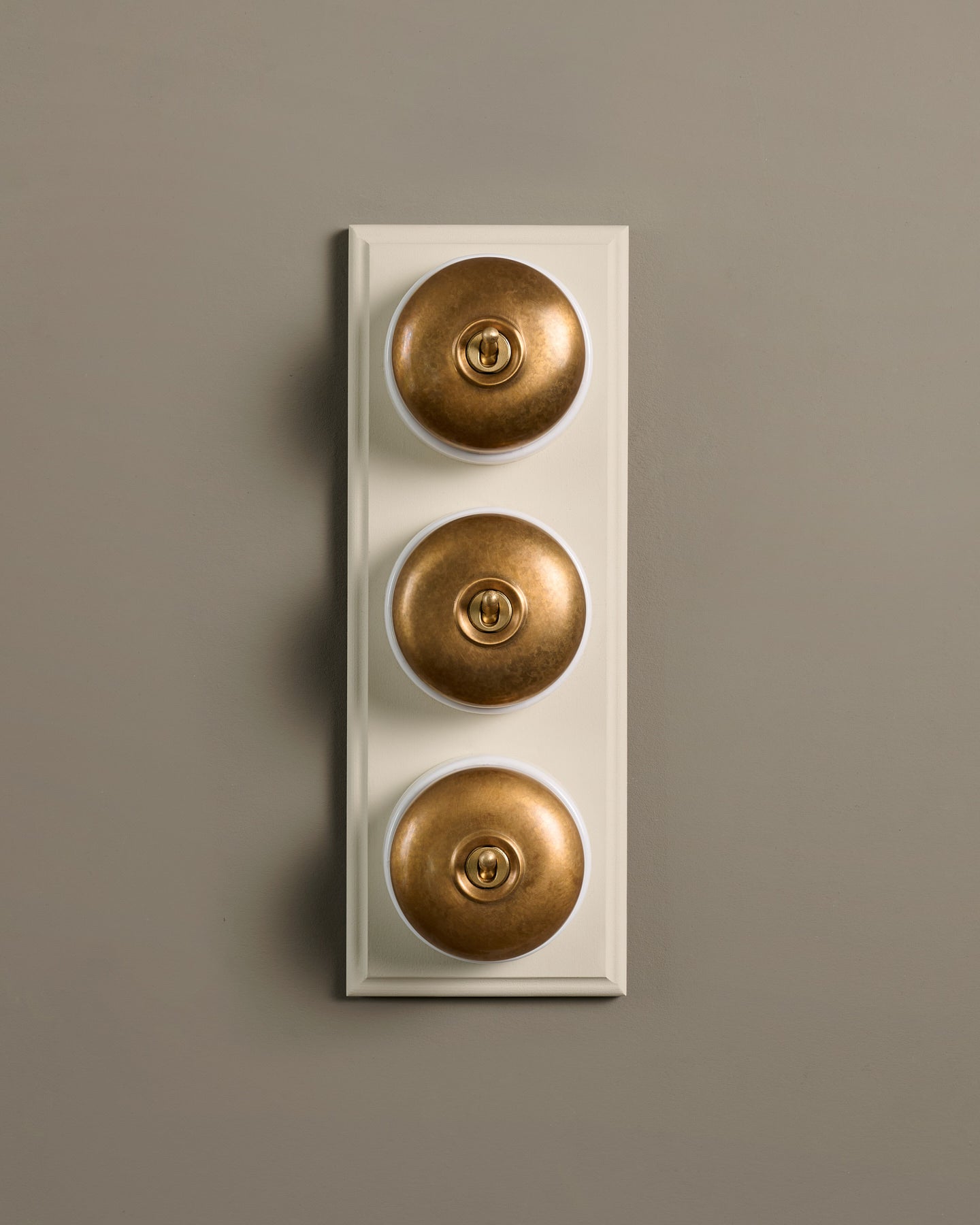 The Dolly Toggle Switch (3 Gang & Primed Maple Pattress) - Aged Brass with White Base.