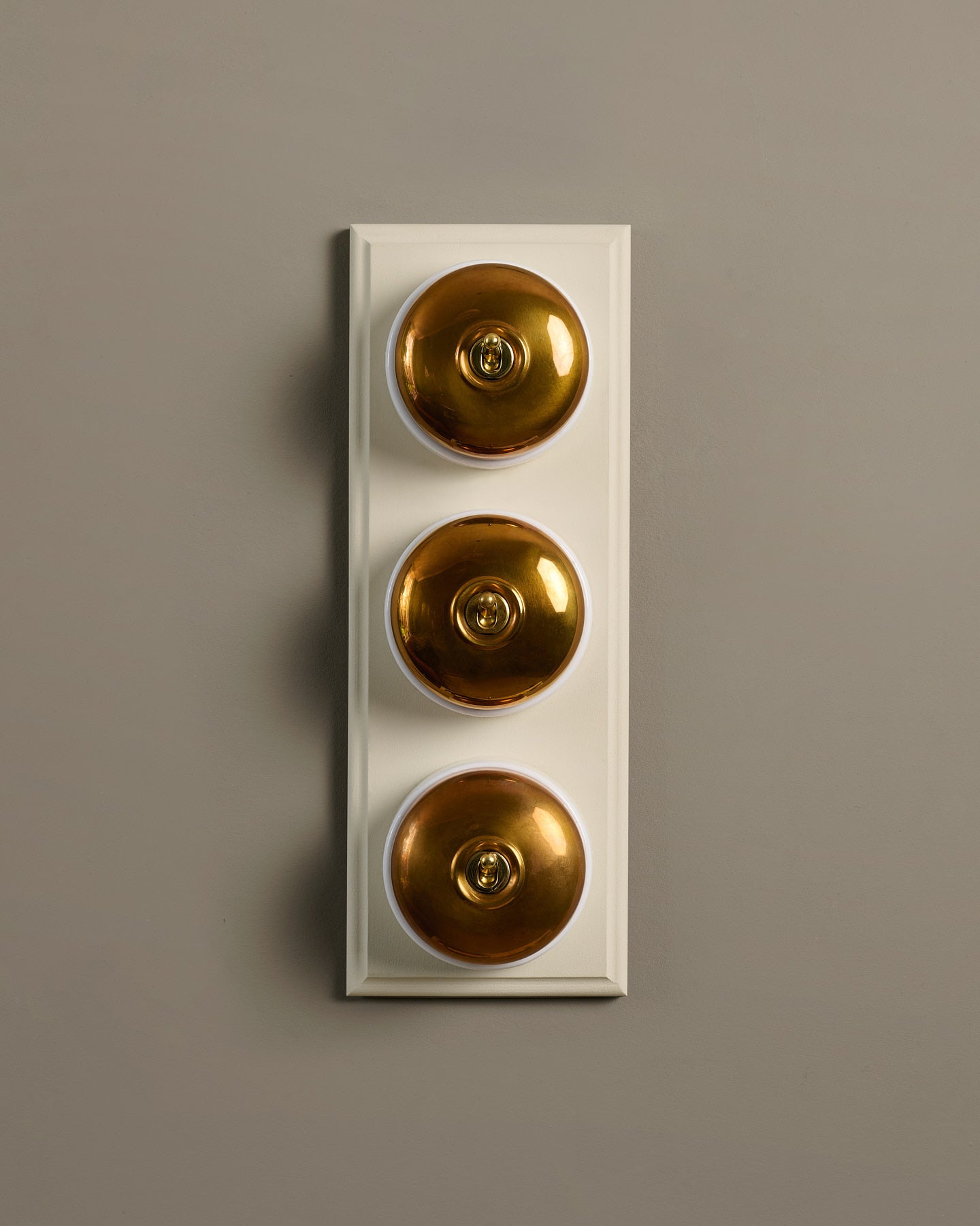 The Dolly Toggle Switch (3 Gang & Primed Maple Pattress) - Heirloom Brass with White Base.