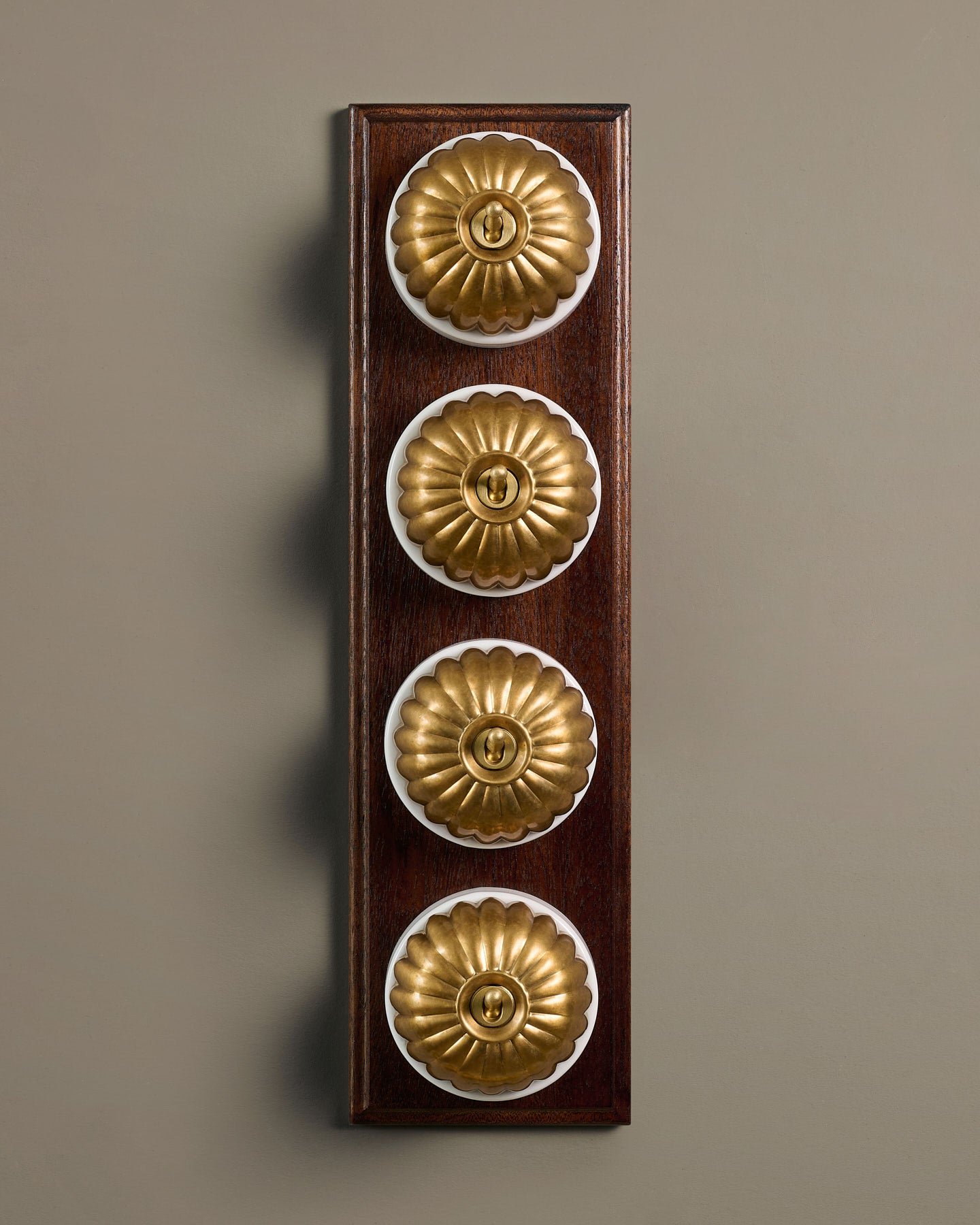 The Jelly Toggle Switch (4 Gang Row & Mahogany Finish Pattress) - Aged Brass with White Base.