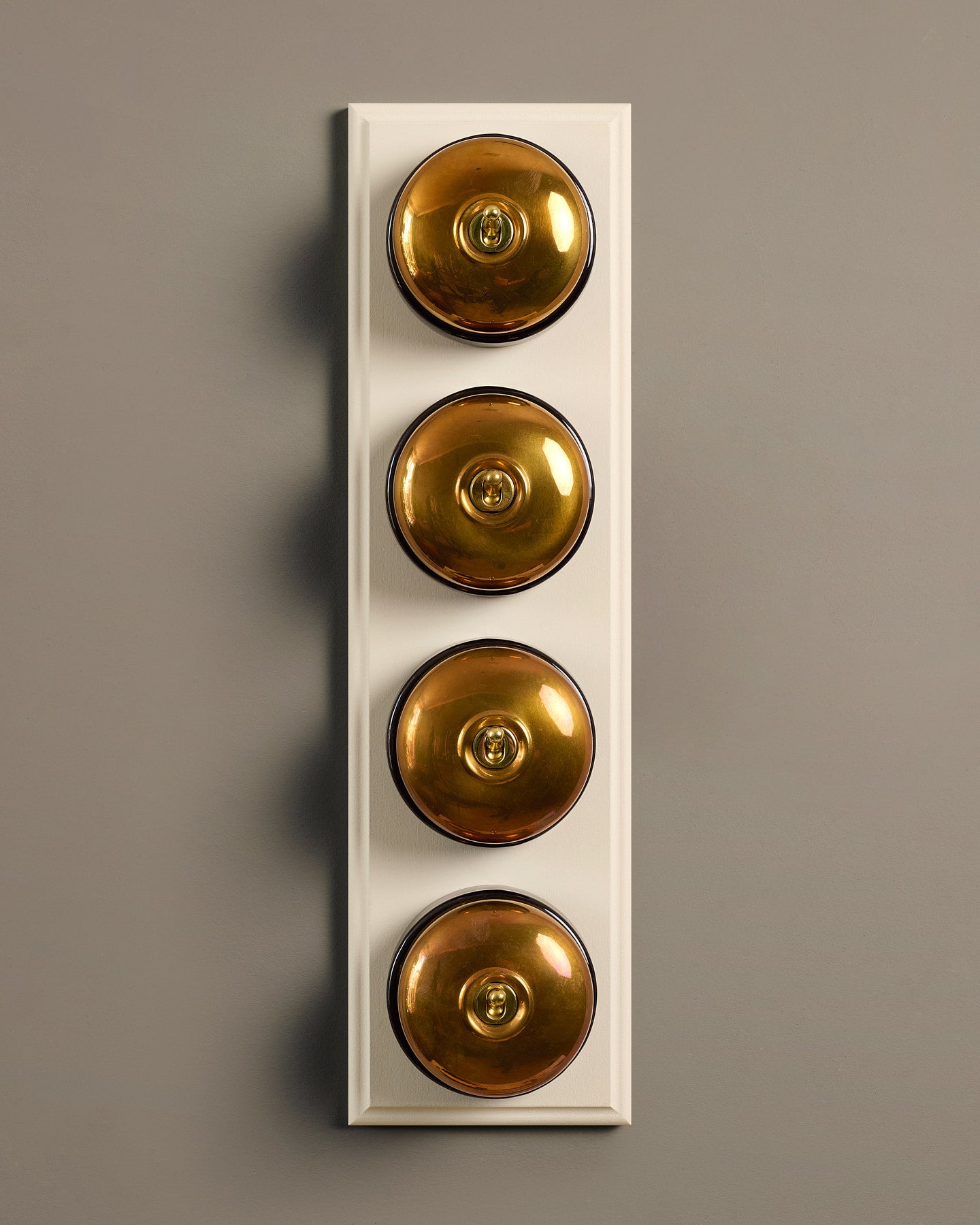 The Dolly Toggle Switch (4 Gang Row & Primed Maple Pattress) - Heirloom Brass with Black Base.