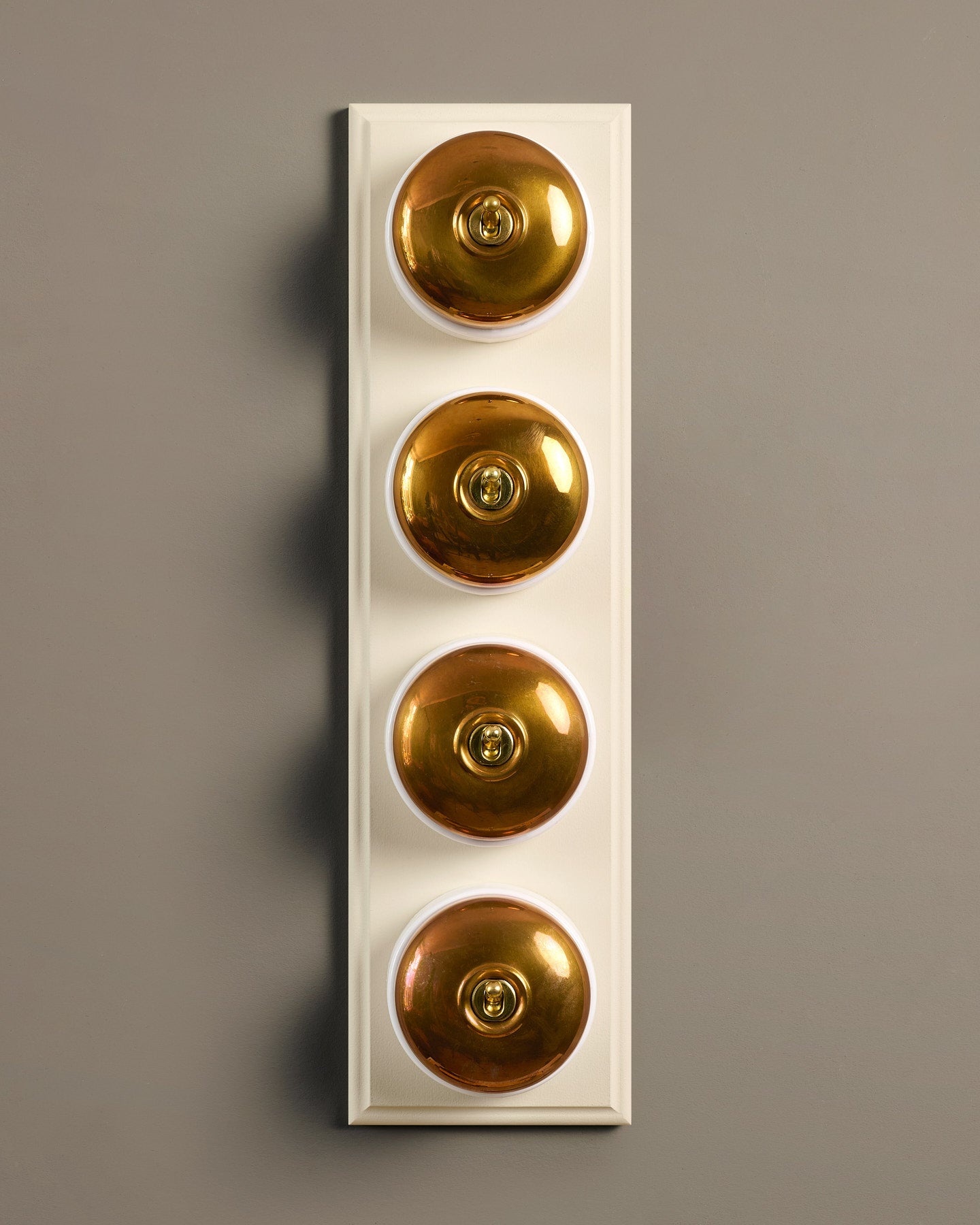 The Dolly Toggle Switch (4 Gang Row & Primed Maple Pattress) - Heirloom Brass with White Base.