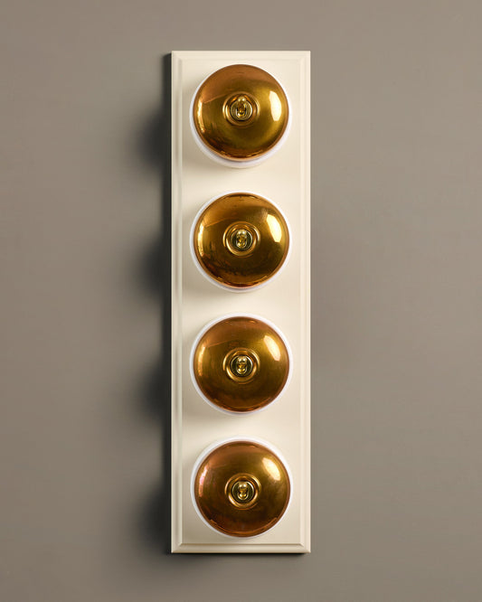 The Dolly Toggle Switch (4 Gang Row & Primed Maple Pattress) - Heirloom Brass with White Base.