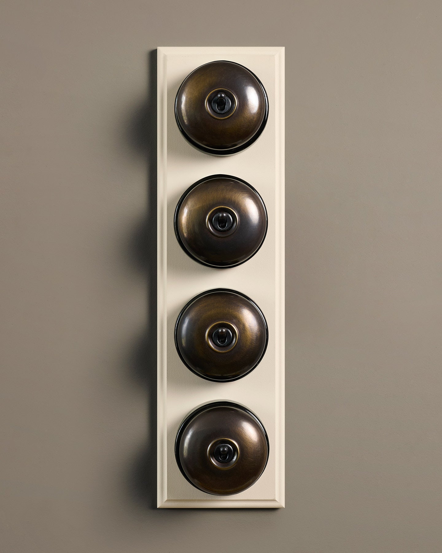 The Dolly Toggle Switch (4 Gang Row & Primed Maple Pattress) - Oxidised Brass with Black Base.