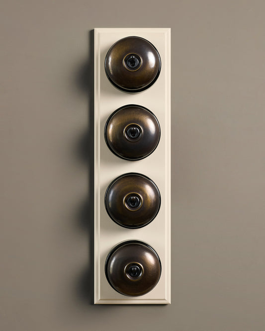 The Dolly Toggle Switch (4 Gang Row & Primed Maple Pattress) - Oxidised Brass with Black Base.