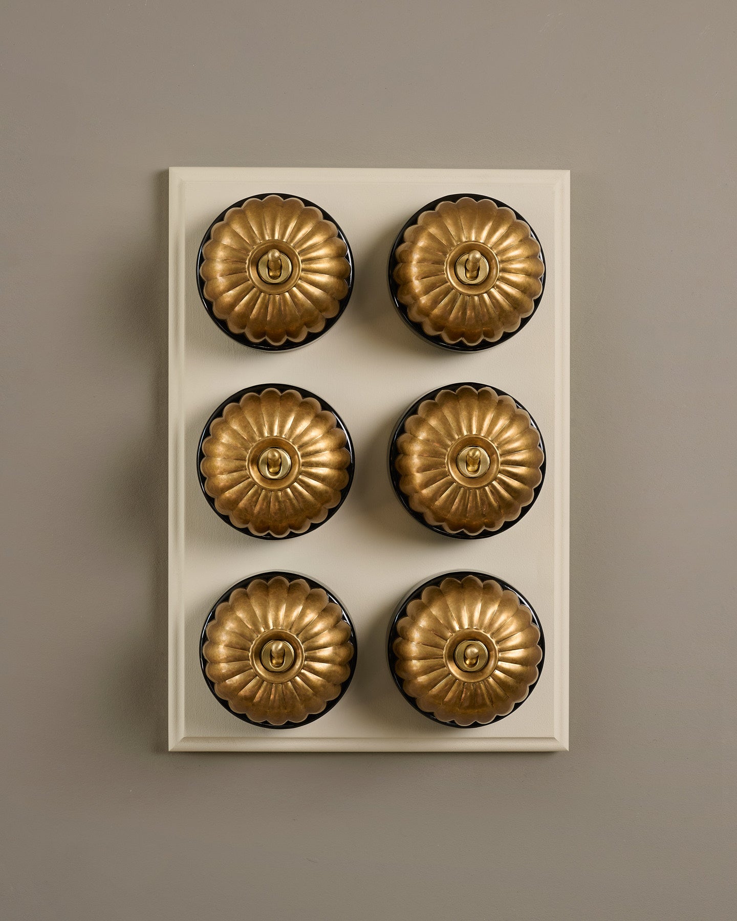 The Jelly Toggle Switch (6 Gang & Primed Maple Pattress) - Aged Brass with Black Base.