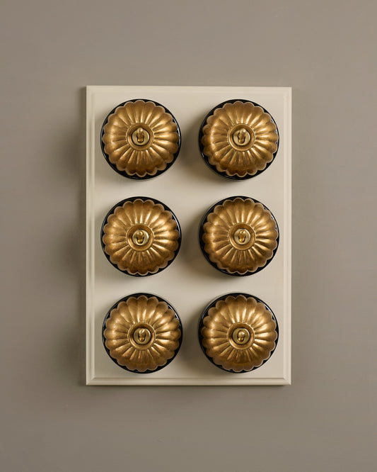 The Jelly Toggle Switch (6 Gang & Primed Maple Pattress) - Aged Brass with Black Base.