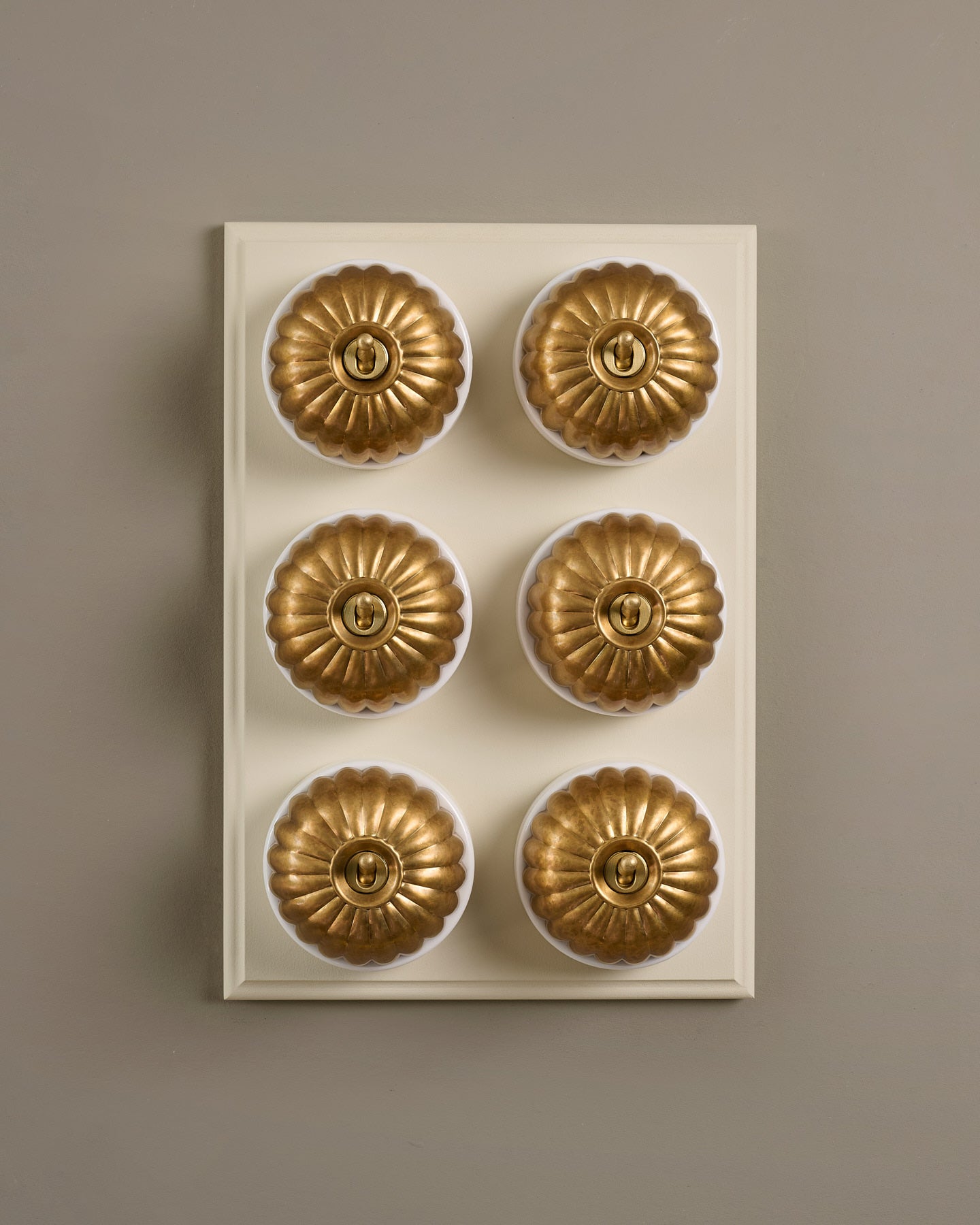 The Jelly Toggle Switch (6 Gang & Primed Maple Pattress) - Aged Brass with White Base.