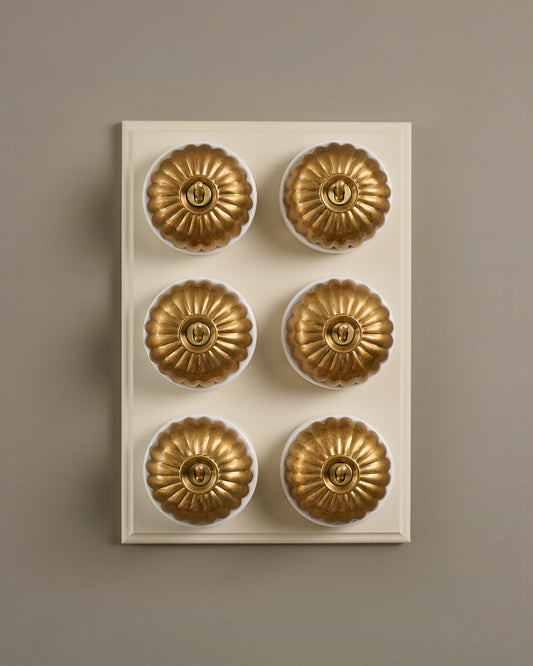 The Jelly Toggle Switch (6 Gang & Primed Maple Pattress) - Aged Brass with White Base.