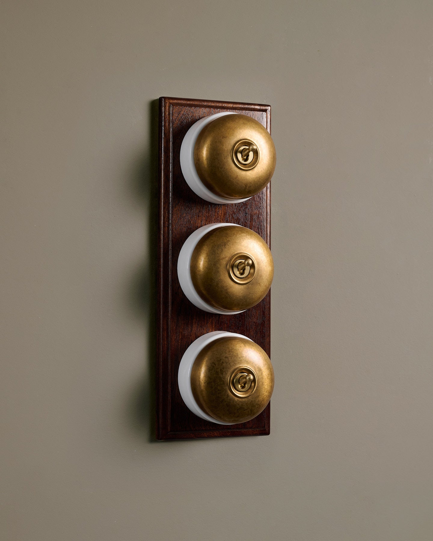 The Dolly Toggle Switch (3 Gang & Mahogany Finish Pattress) - Aged Brass with White Base.