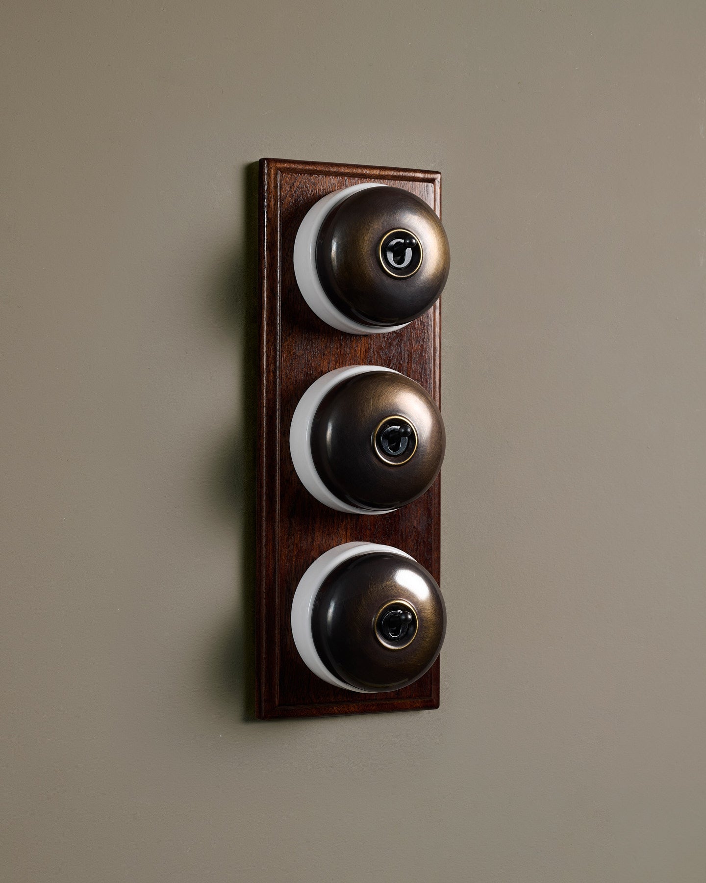 The Dolly Toggle Switch (3 Gang & Mahogany Finish Pattress) - Oxidised Brass with White Base.