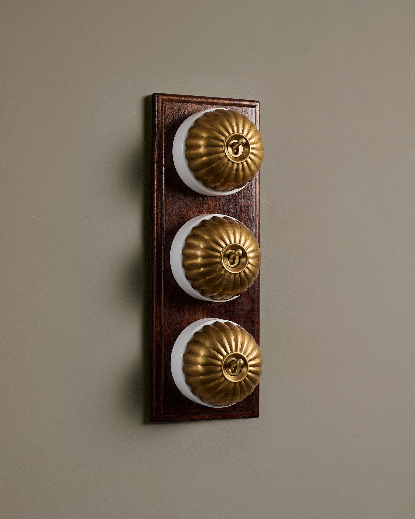 The Jelly Toggle Switch (3 Gang & Mahogany Finish Pattress) - Aged Brass with White Base.