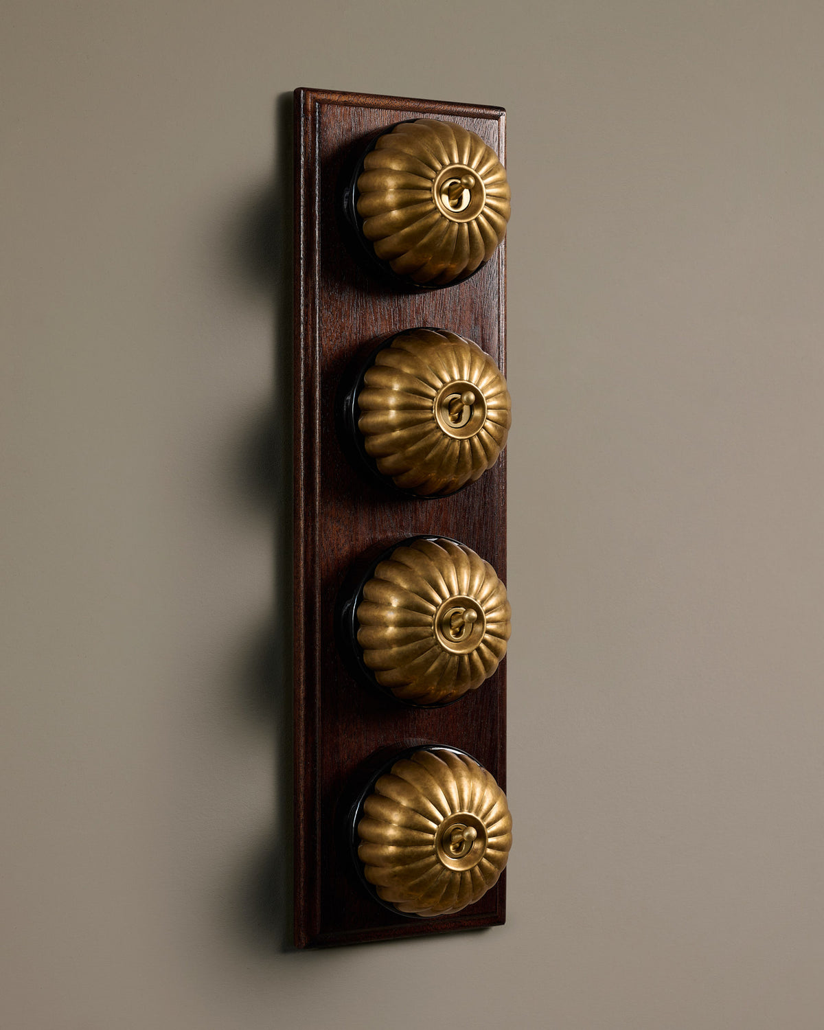 The Jelly Toggle Switch (4 Gang Row & Mahogany Finish Pattress) - Aged Brass with Black Base. TEST
