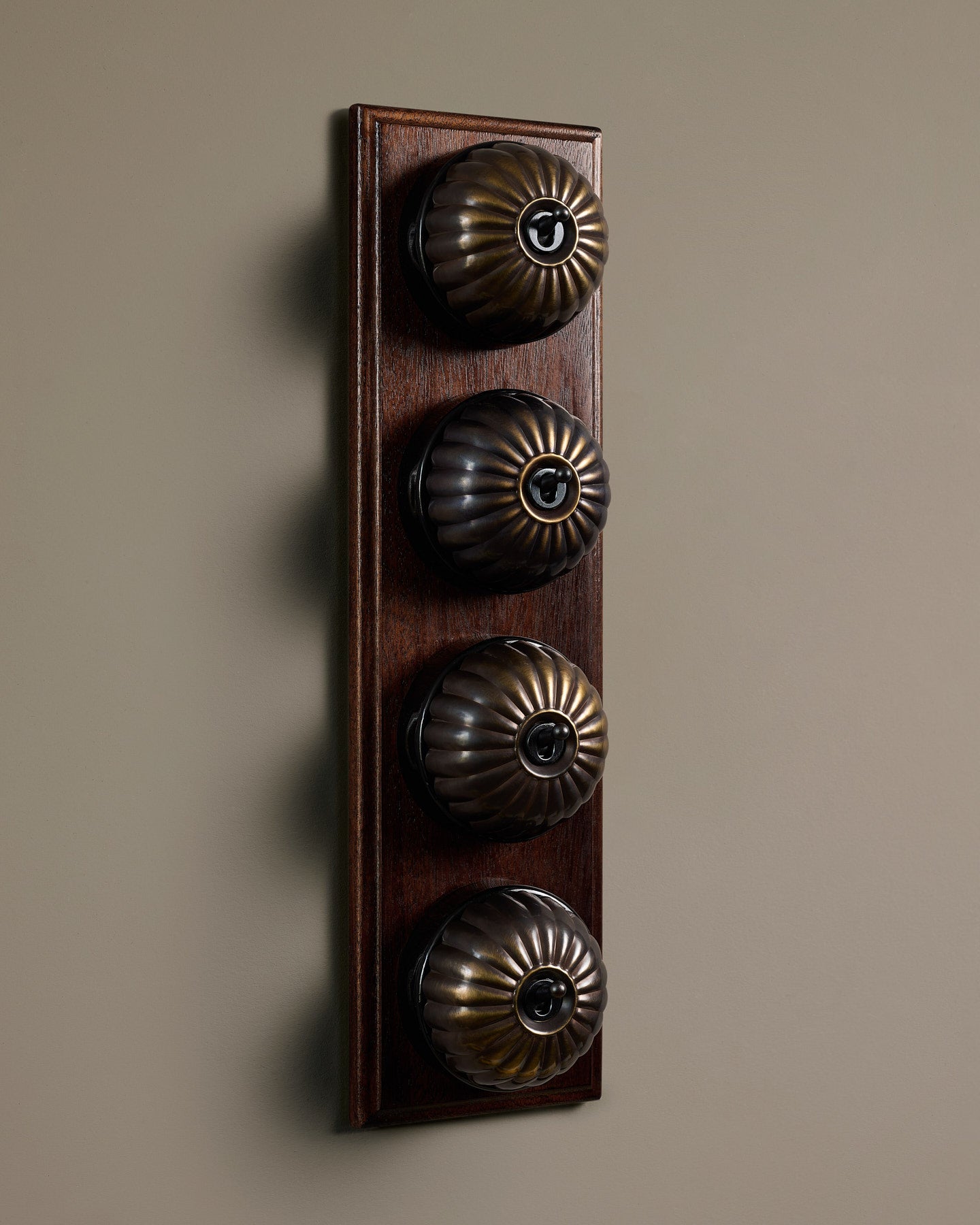 The Jelly Toggle Switch (4 Gang Row & Mahogany Finish Pattress) - Oxidised Brass with Black Base.