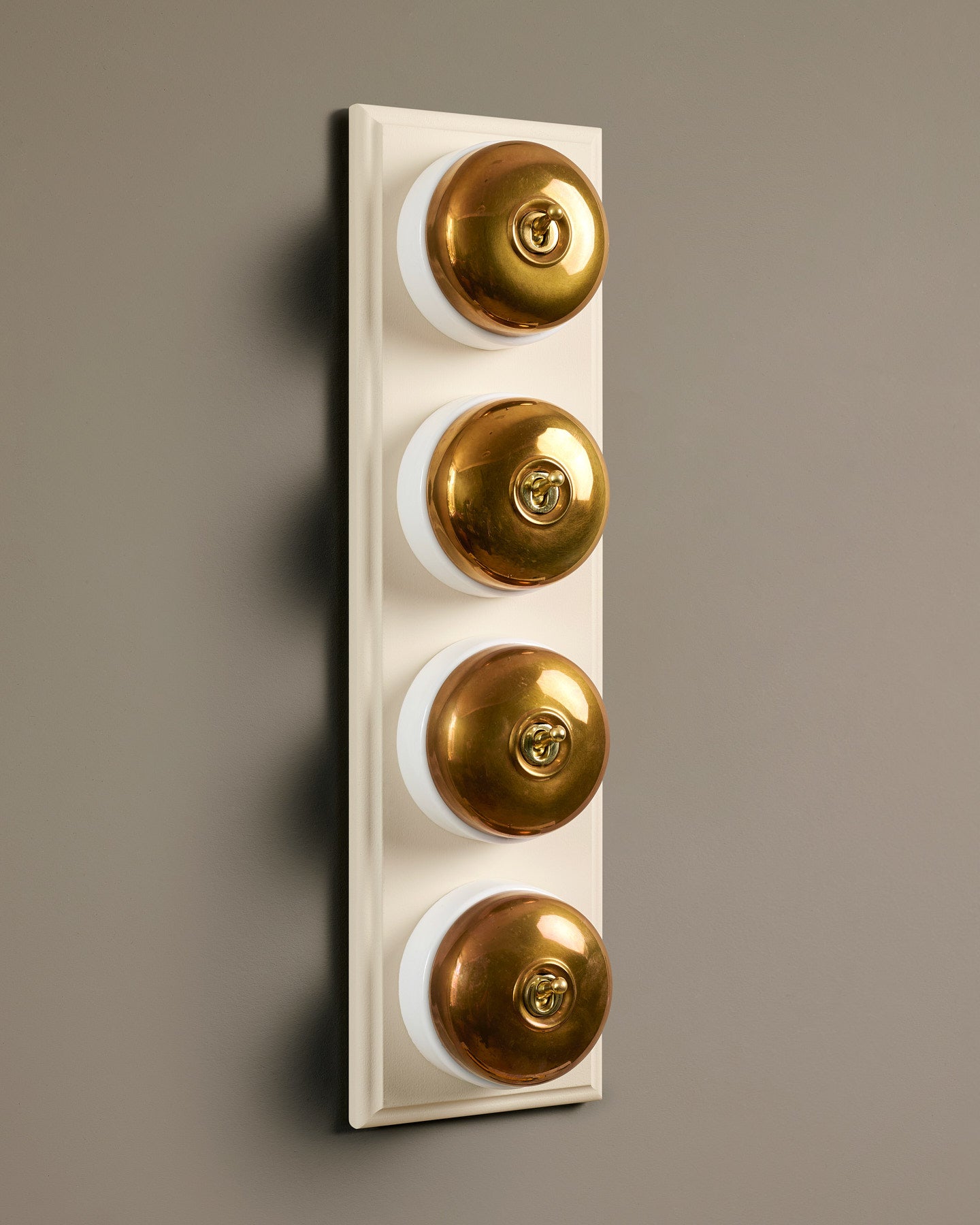 The Dolly Toggle Switch (4 Gang Row & Primed Maple Pattress) - Heirloom Brass with White Base.