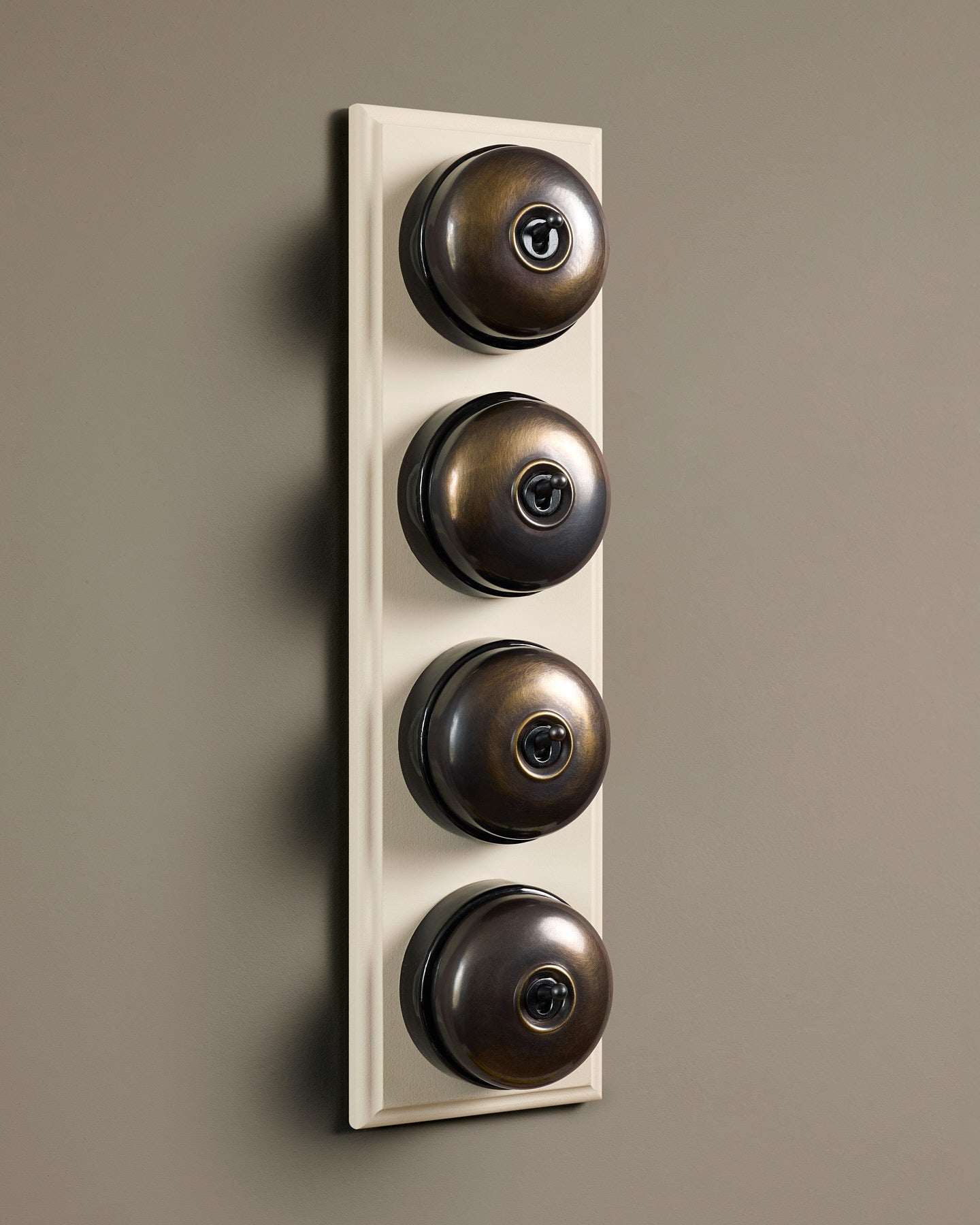 The Dolly Toggle Switch (4 Gang Row & Primed Maple Pattress) - Oxidised Brass with Black Base.