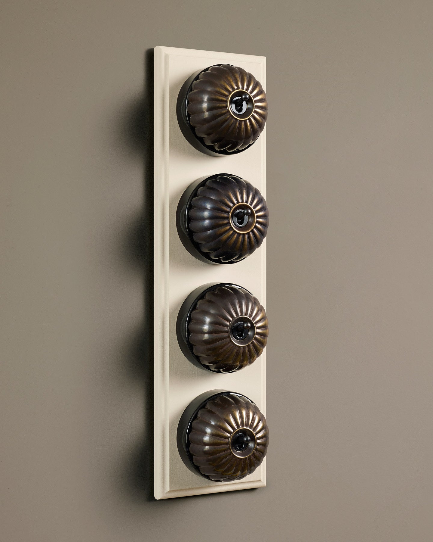 The Jelly Toggle Switch (4 Gang Row & Primed Maple Pattress) - Oxidised Brass with Black Base.
