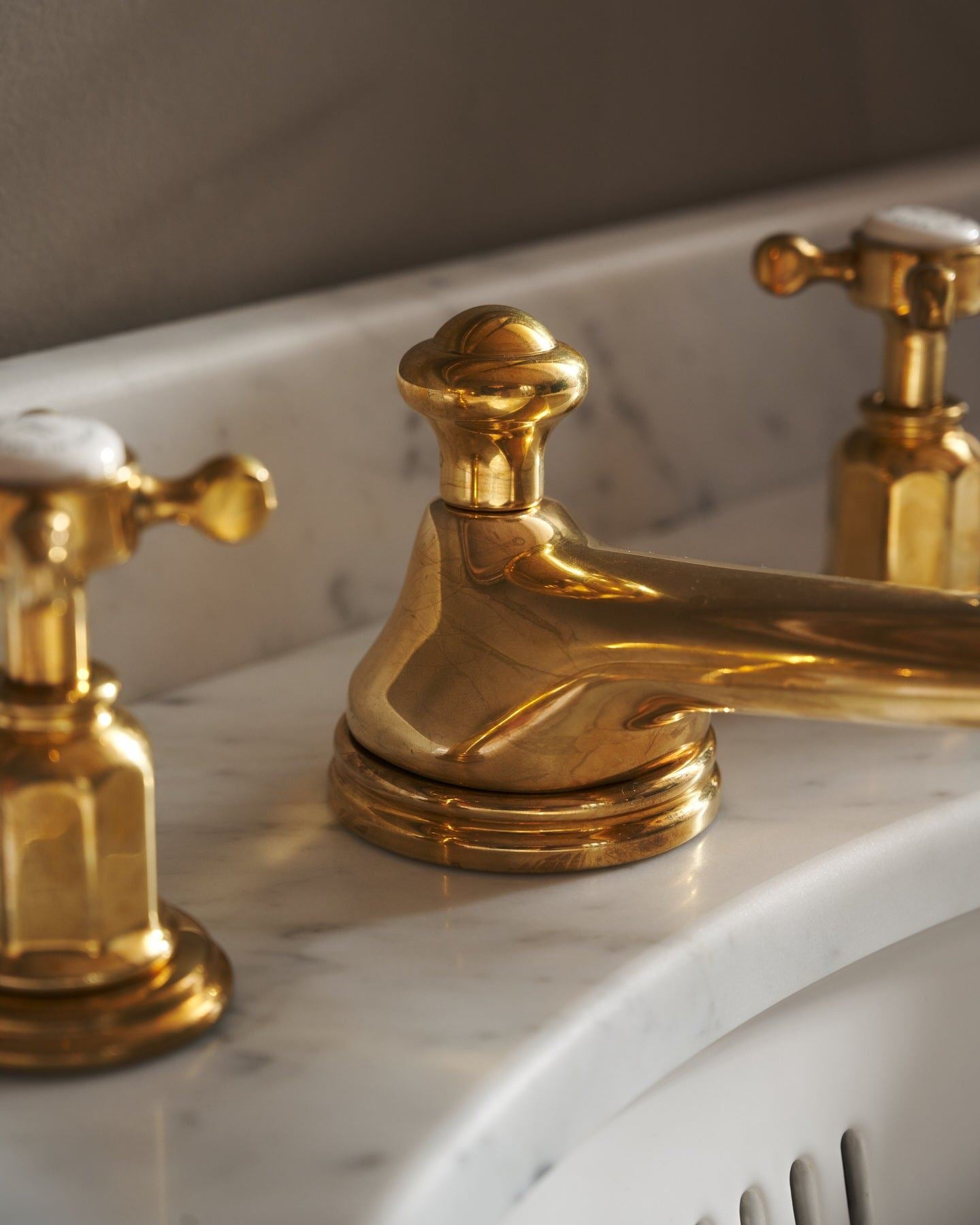 A close-up oblique view of an aged brass mixer tap with crosshead handles for a bathroom basin sink.