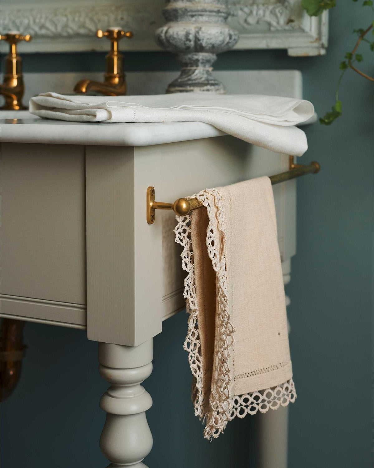 A detailed view of an aged brass towel rail attached to the right side of a Victorian-inspired washstand, a vintage lace hand towel hangs from the rail. | Right Towel Rail shown TEST