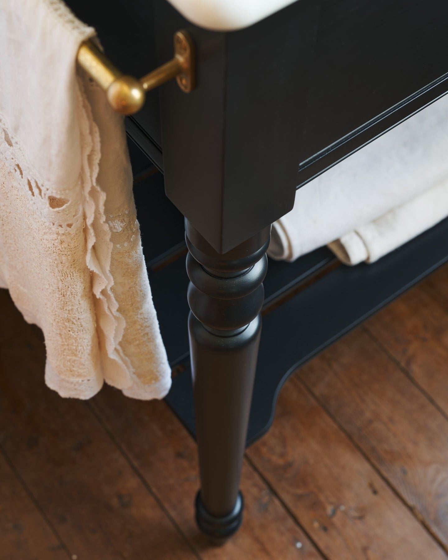 A close-up oblique view of a pair of aged brass pillar taps with crosshead handles for a bathroom basin sink.