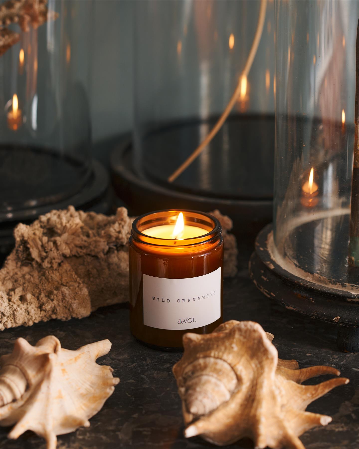 A lit medium scented candle in a brown glass jar with one wick, on a polished quartz worktop.