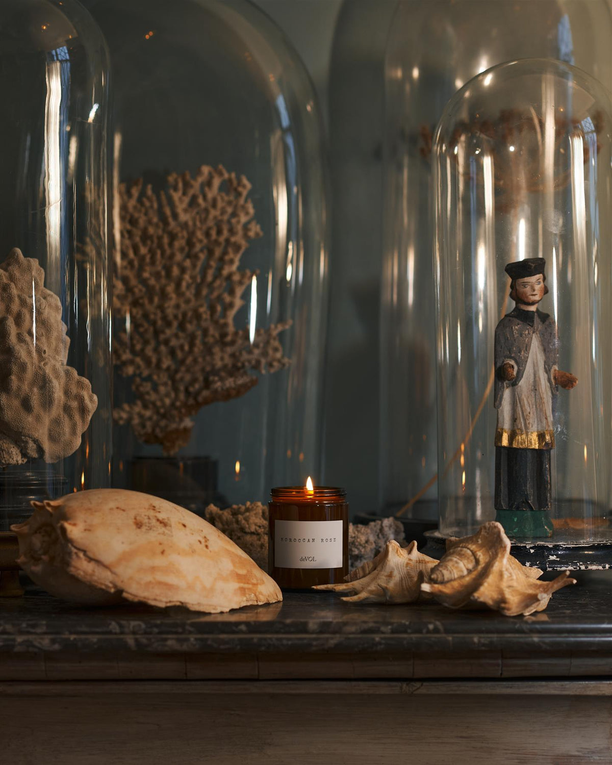 A lit medium scented candle in a brown glass jar with one wick, on a polished quartz worktop. TEST