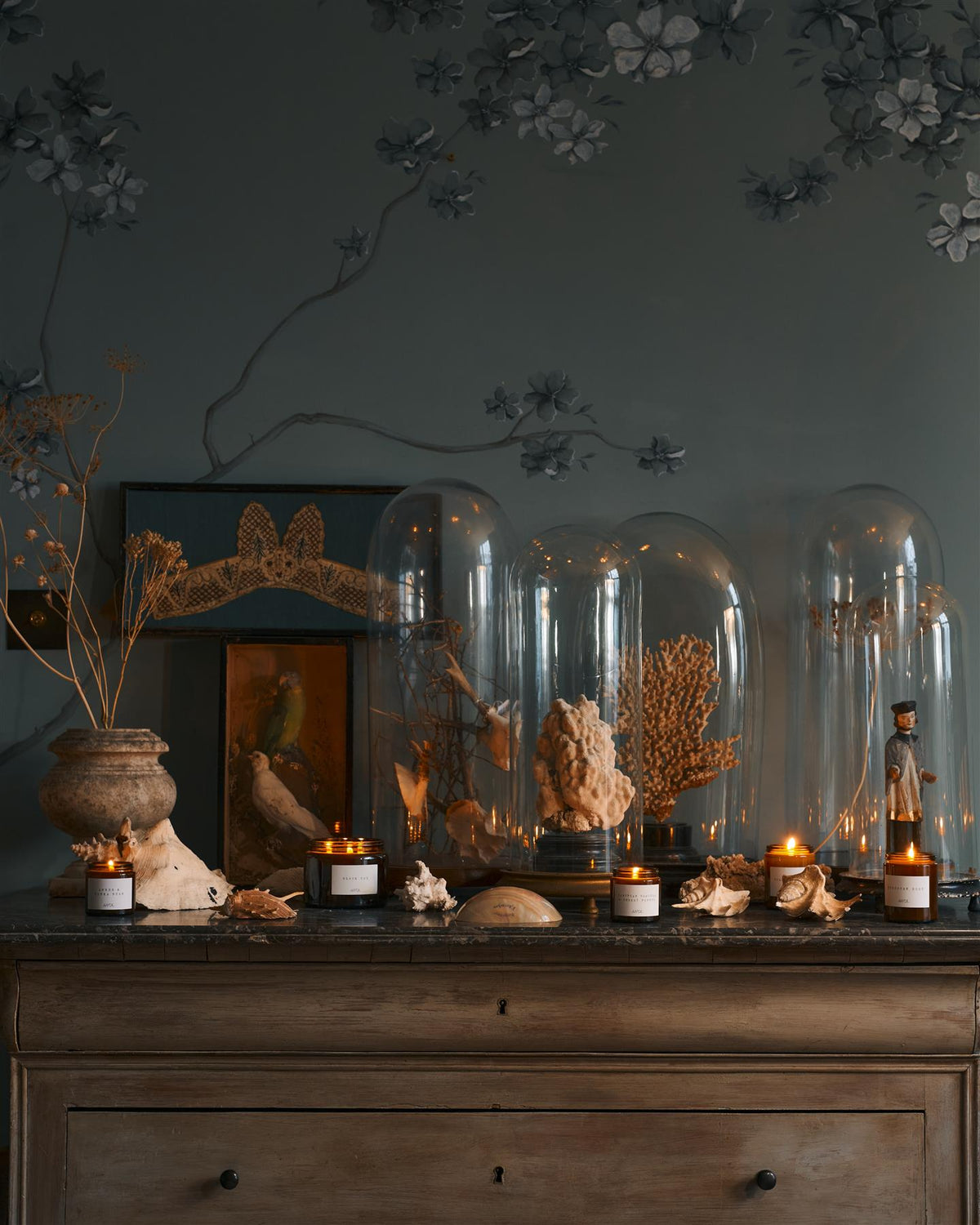 A collection of scented candles in brown glass jars with black lids in a vintage cupboard. TEST