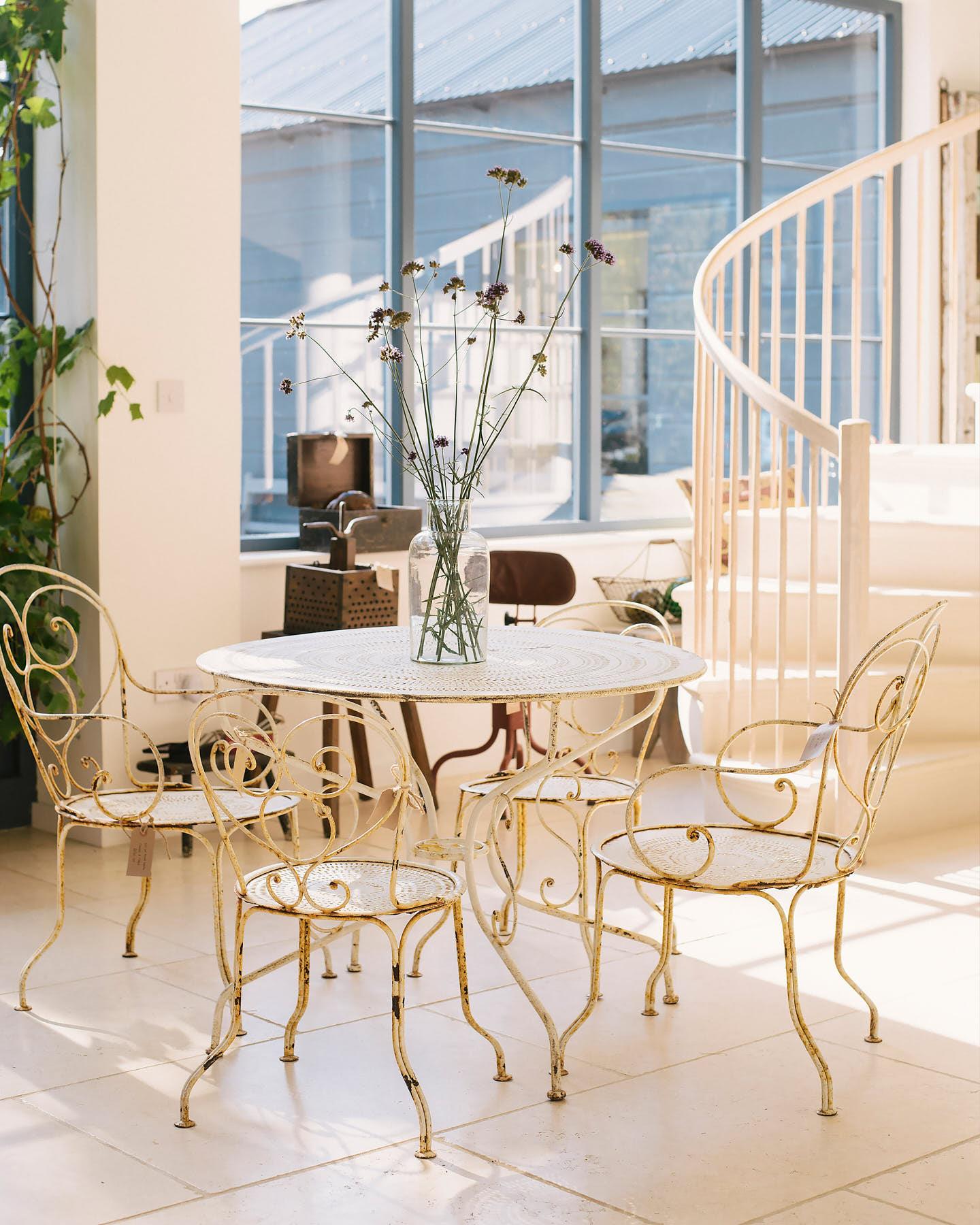 A wide shot looking across deVOL's flooring showroom, with high vaulting ceilings, a unique marble spiral staircase, pale off-white walls and smooth, creamy Light Jerusalem Limestone flooring.
