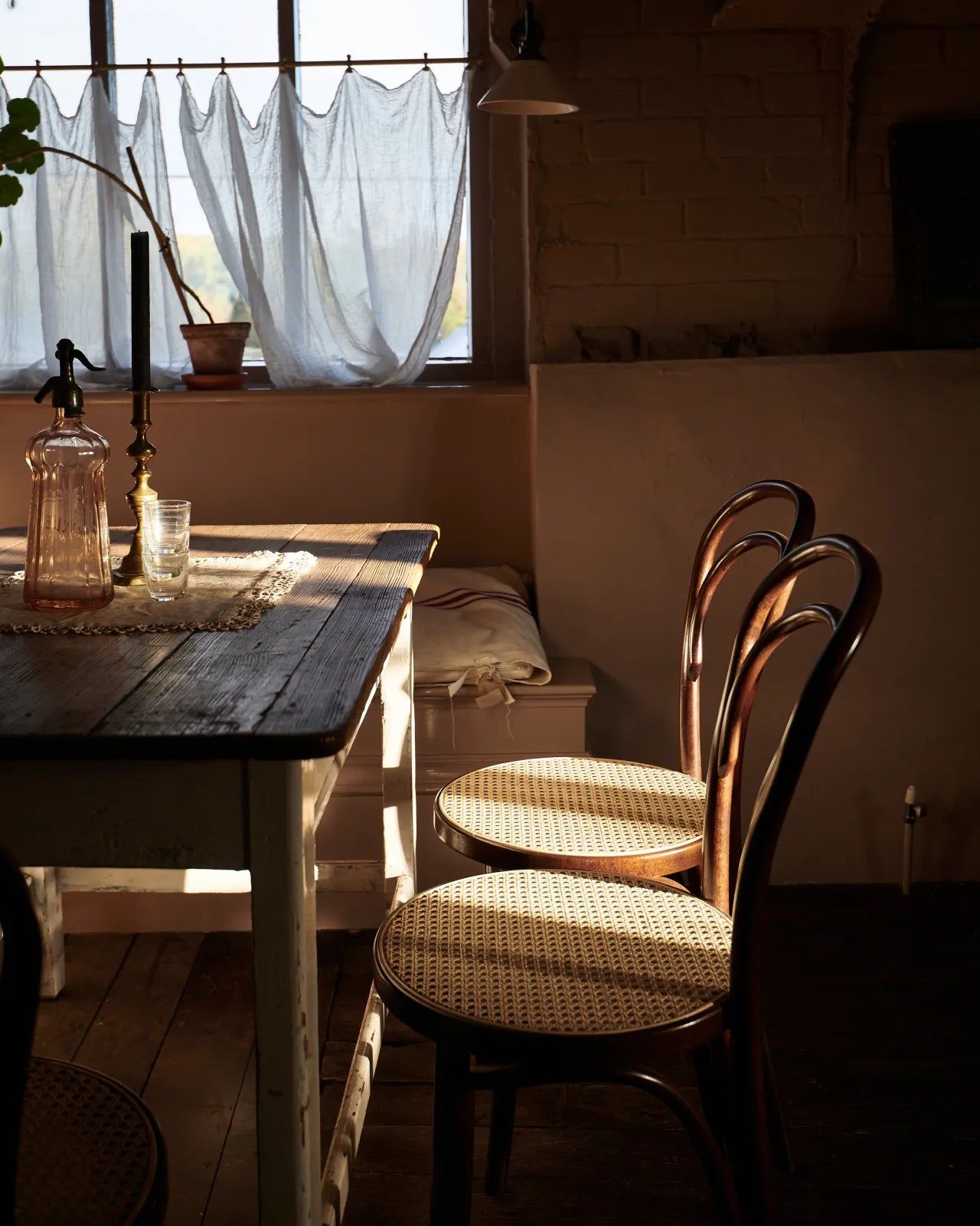 An oblique view of a grand oak prep table with a Carrara marble worktop with a row of cafÈ-style bar stools with dark stained frames and light woven ratten seats.