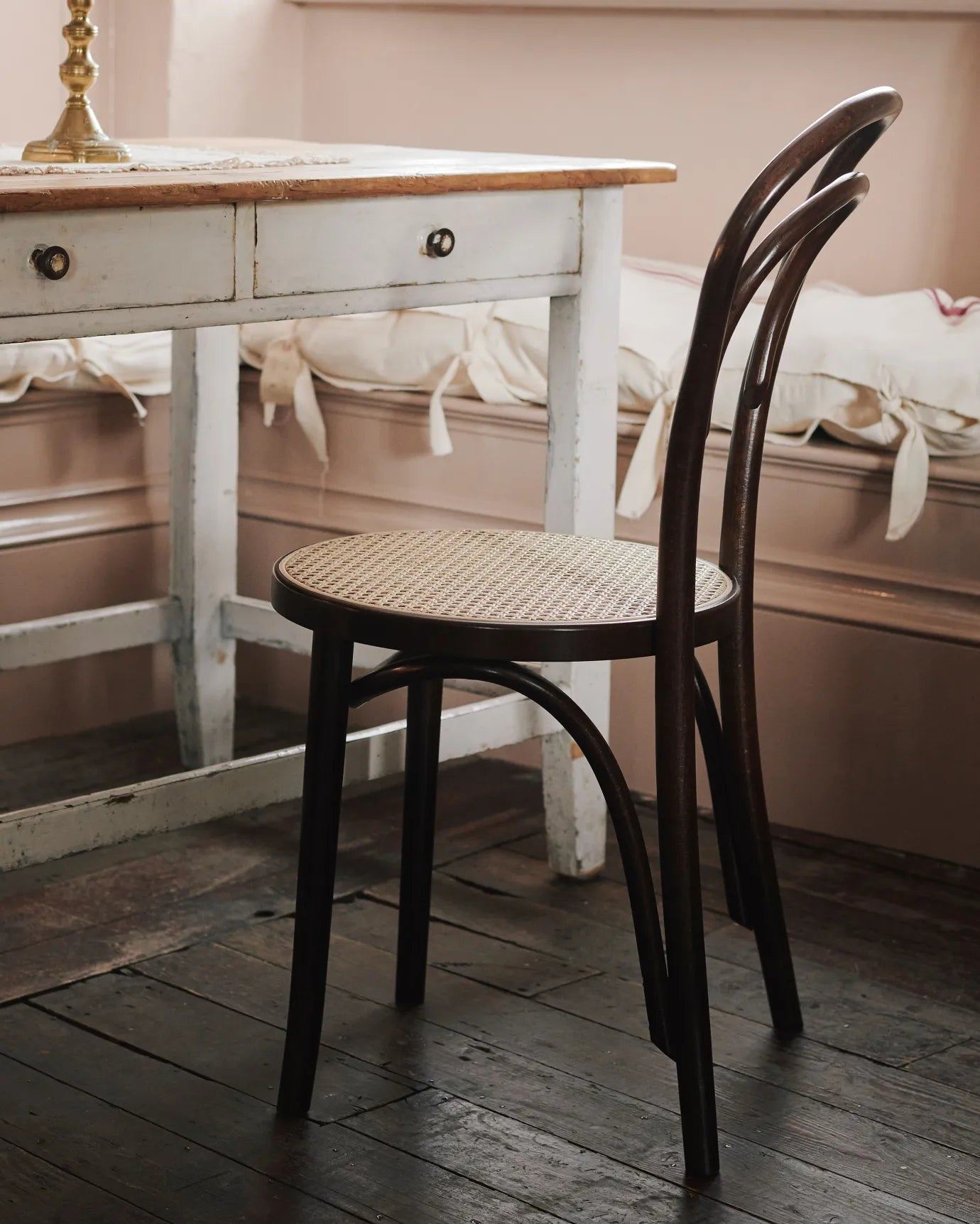 A close-up oblique view two cafÈ-style bar stools with dark stained frames and light woven ratten seats.