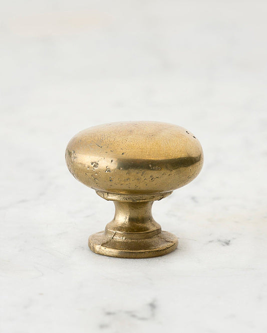A 'Large' classic knob for a kitchen cupboard or drawer with an aged brass finish and unique dented textures that makes it look like a beloved, well aged brass from centuries ago.