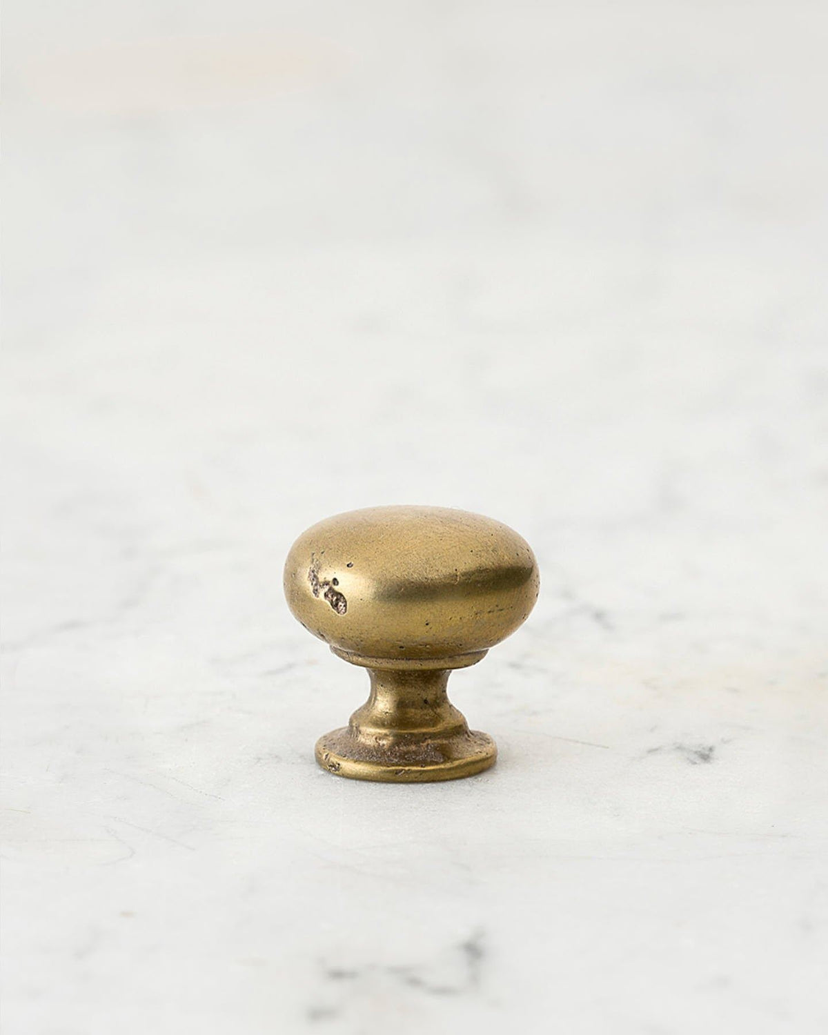 A 'Large' classic knob for a kitchen cupboard or drawer with an aged brass finish and unique dented textures that makes it look like a beloved, well aged brass from centuries ago. TEST