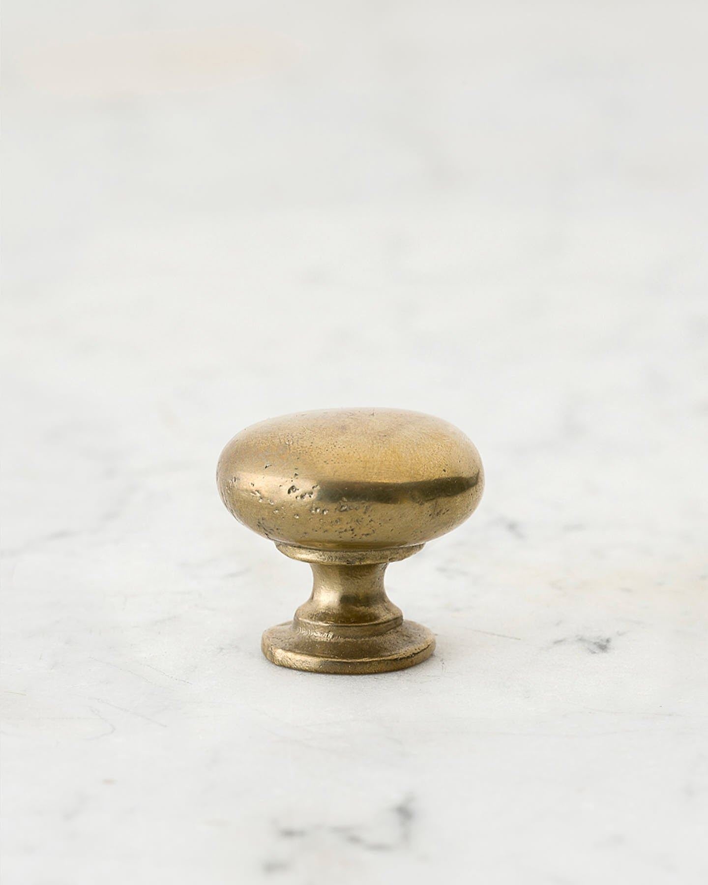 A 'Small' classic knob for a kitchen cupboard or drawer with an aged brass finish and unique dented textures that makes it look like a beloved, well aged brass from centuries ago.