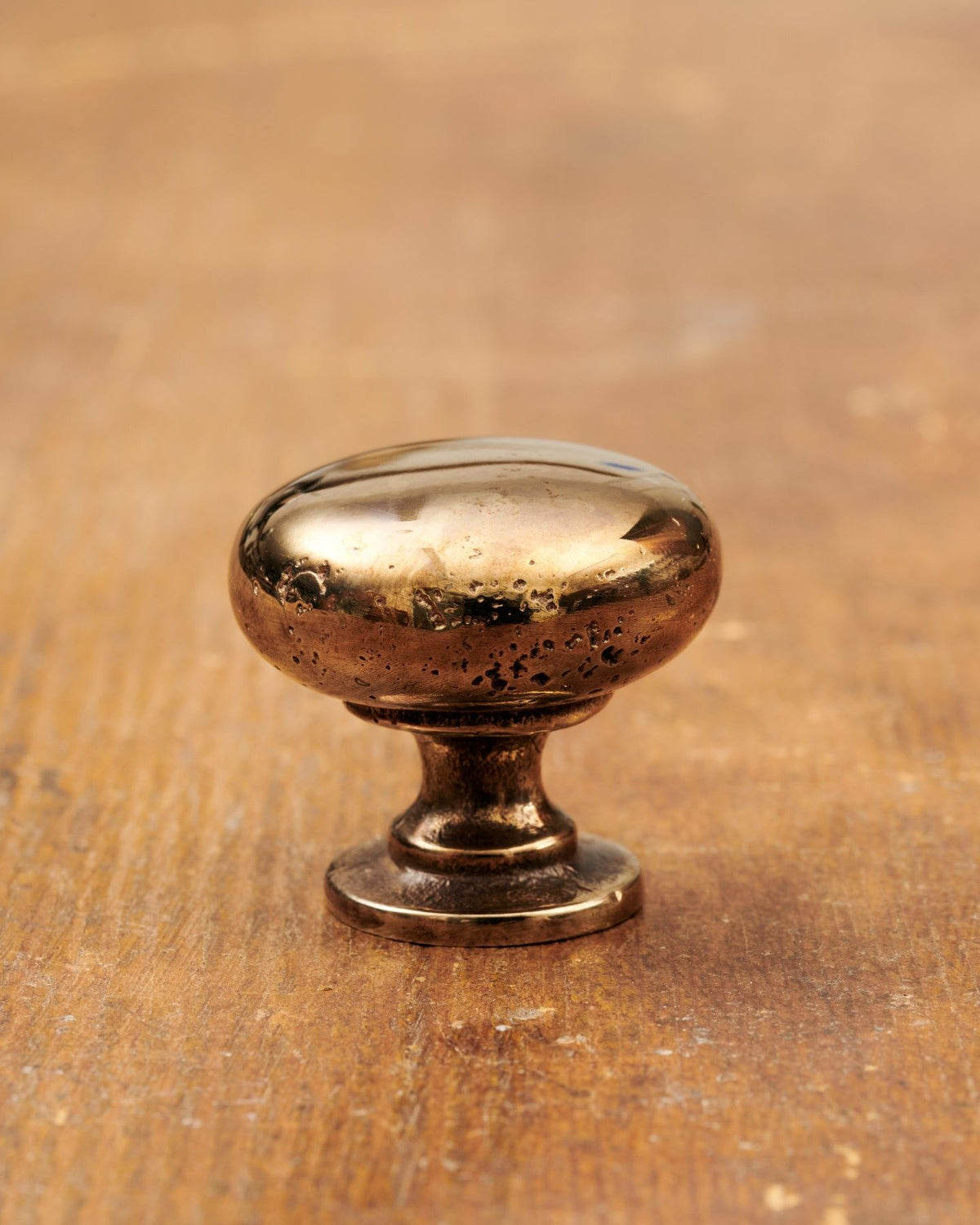 A 'Medium' classic knob for a kitchen cupboard or drawer with a warm burnished brass finish and unique dented textures as if was made by an artisan blacksmith centuries ago. TEST