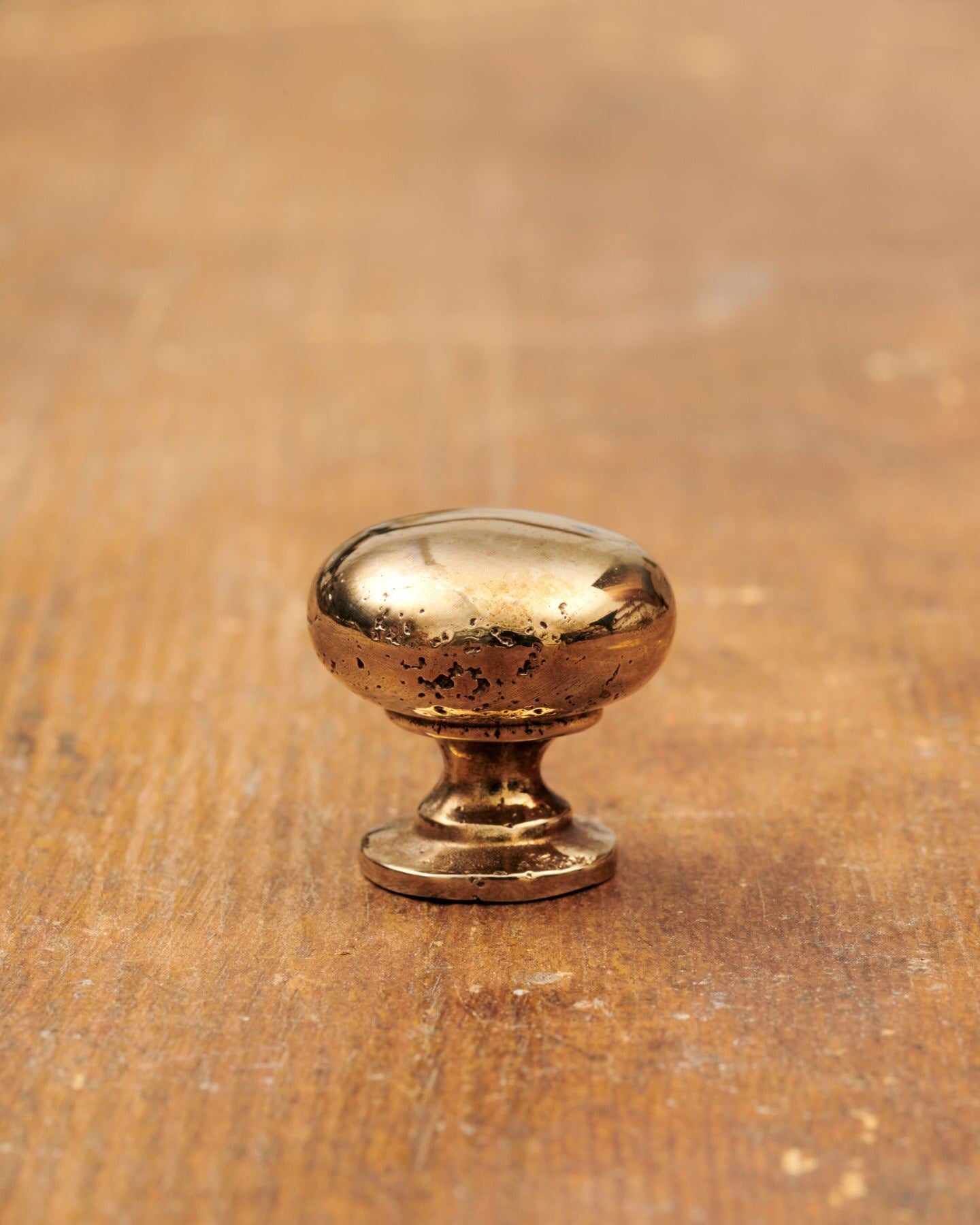 A 'Small' classic knob for a kitchen cupboard or drawer with a warm burnished brass finish and unique dented textures as if was made by an artisan blacksmith centuries ago.