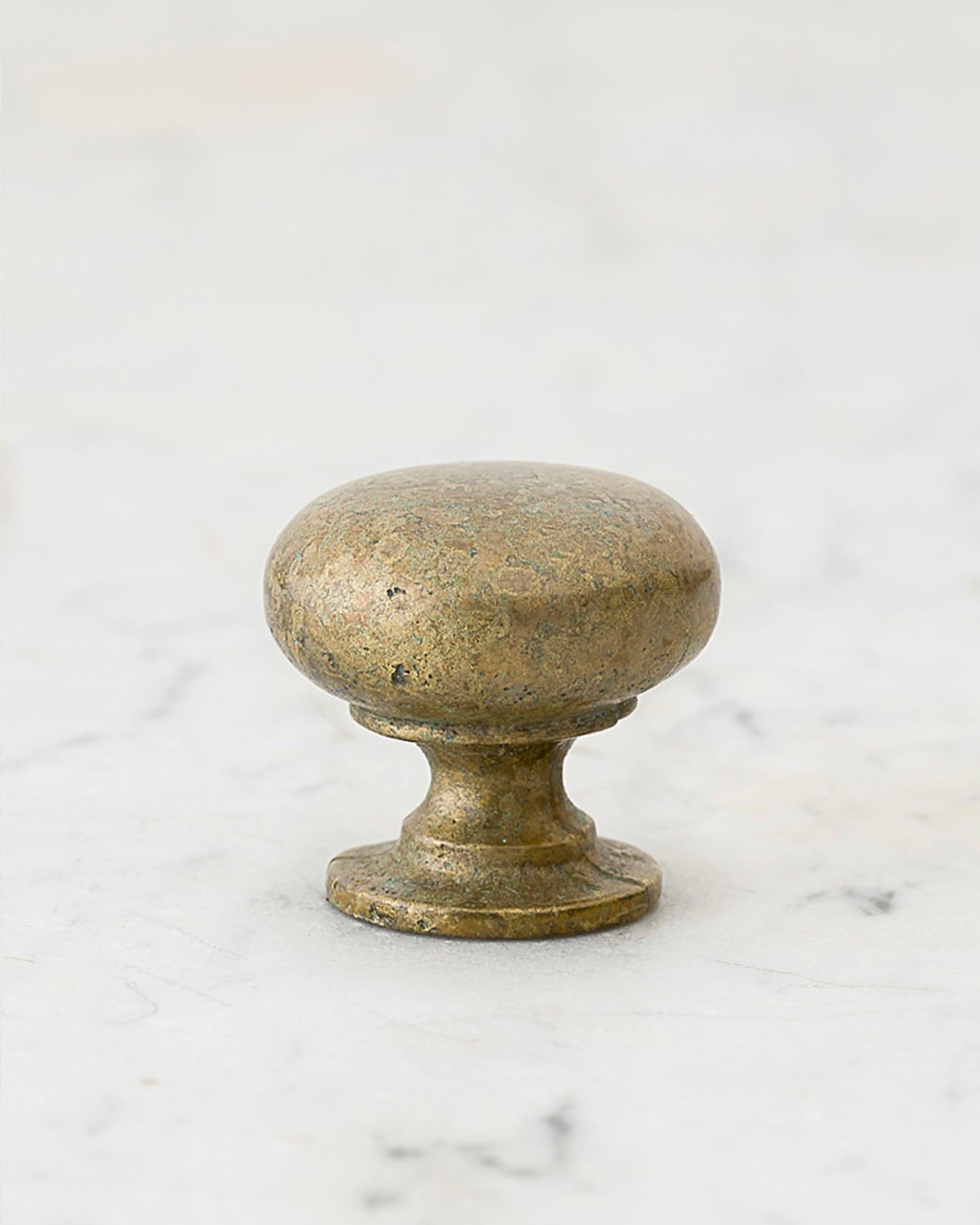 A 'Medium' classic knob for a kitchen cupboard or drawer with an aged verdigris brass finish and unique dented textures as if was made by an artisan blacksmith centuries ago.