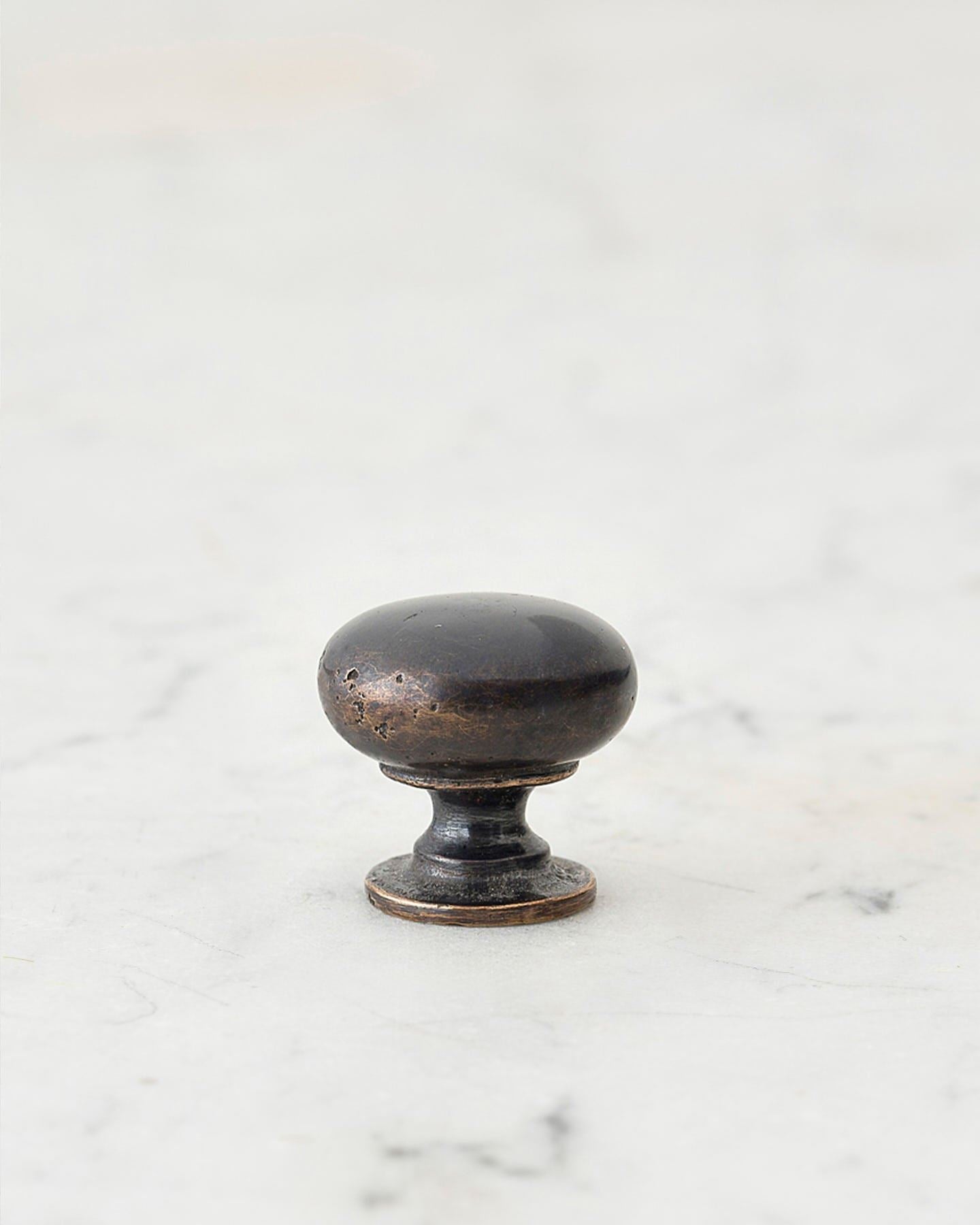A 'Petite' classic knob for a kitchen cupboard or drawer with a dark oxidised bronze finish and unique dented textures as if was made by an artisan blacksmith centuries ago.