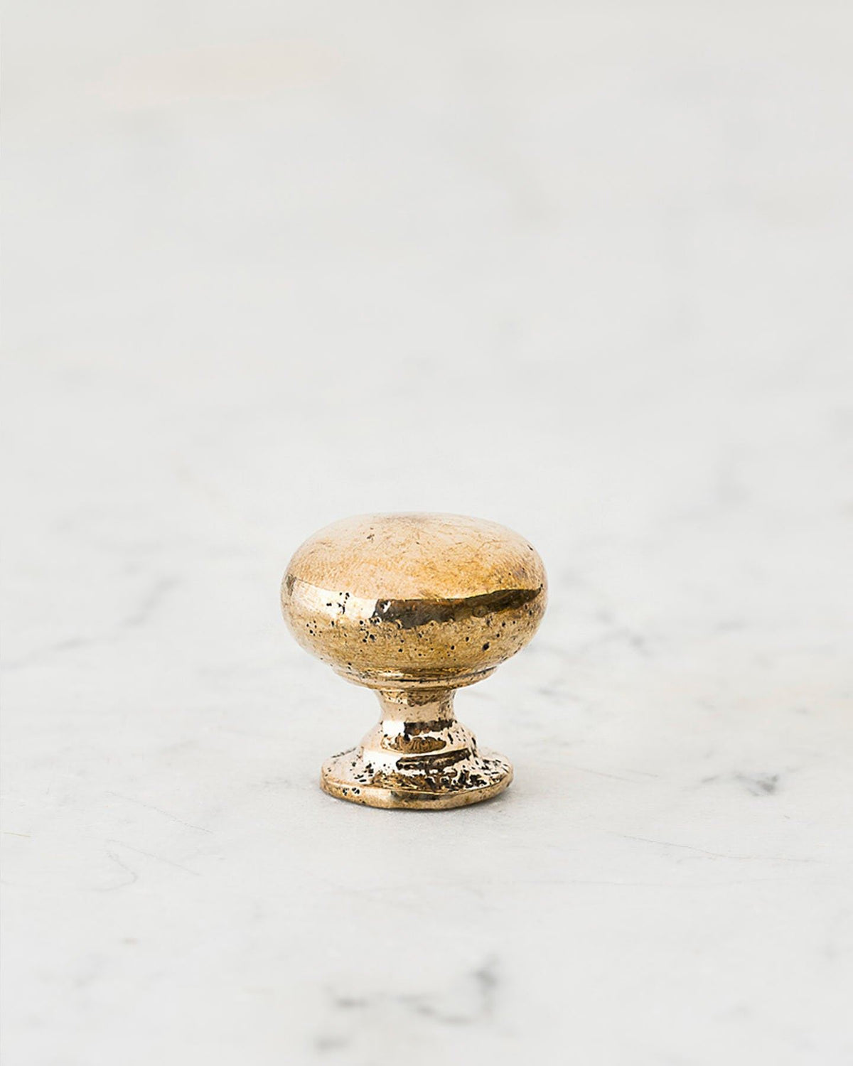 A 'Petite' classic knob for a kitchen cupboard or drawer with a bright polished bronze finish and unique dented textures that makes it look like a beloved, well aged bronze from centuries ago. TEST